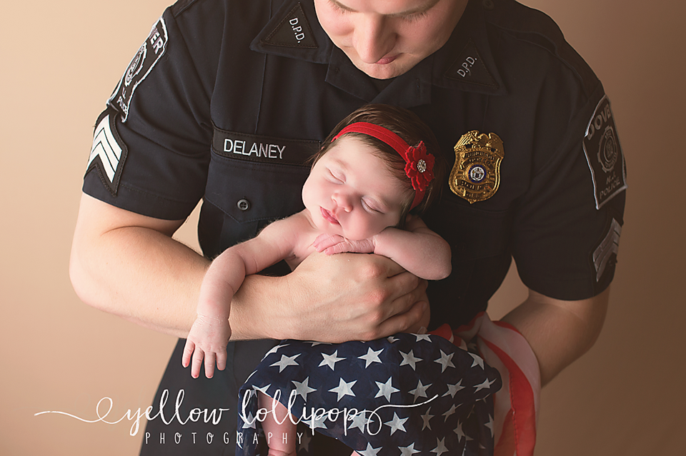 police offier holding his newborn daughter wrapped in a flag scarf 