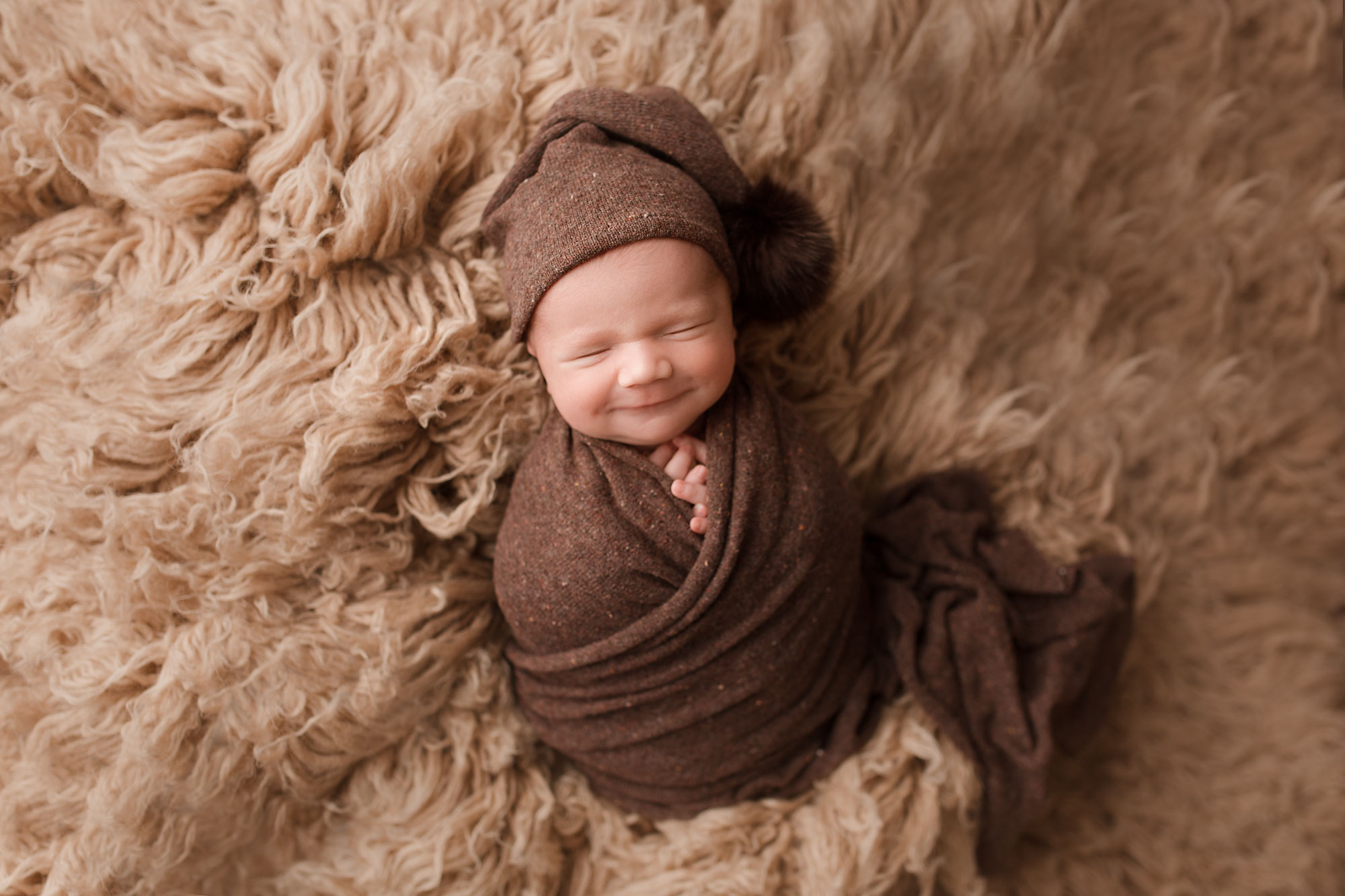 smiling baby wrapped up on a fuzzy rug newborn photos morris county nj
