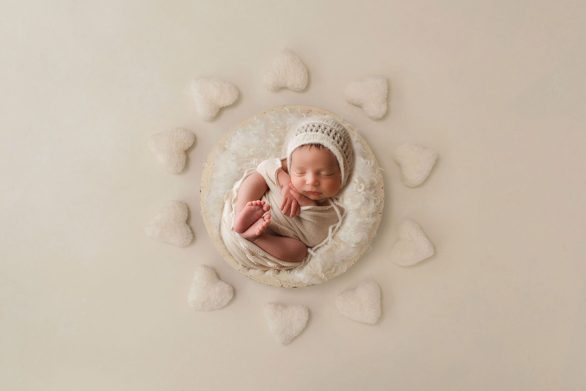 digital composite of a newborn baby in a basket with white hearts around 