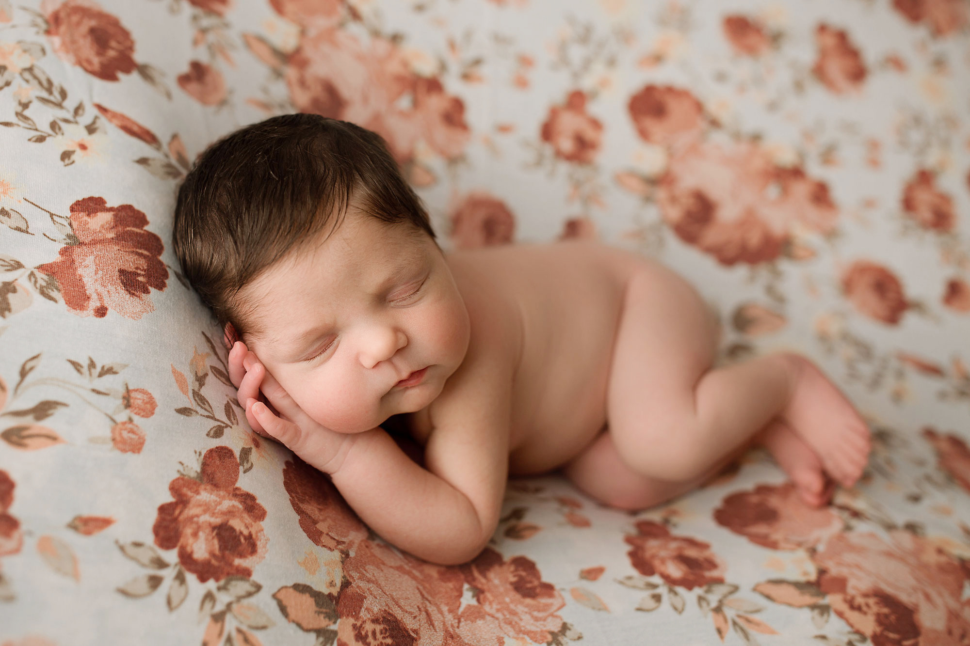 newborn sleeping on a floral blanket, side lying pose