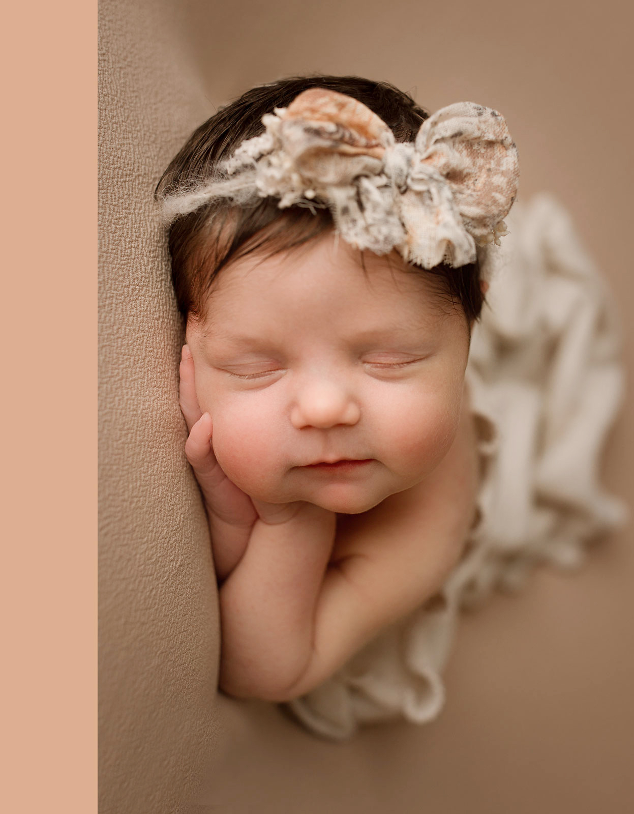 baby girl sleeping on a neutral backdrop, wrapped with a headband in her hair, baby posing 
