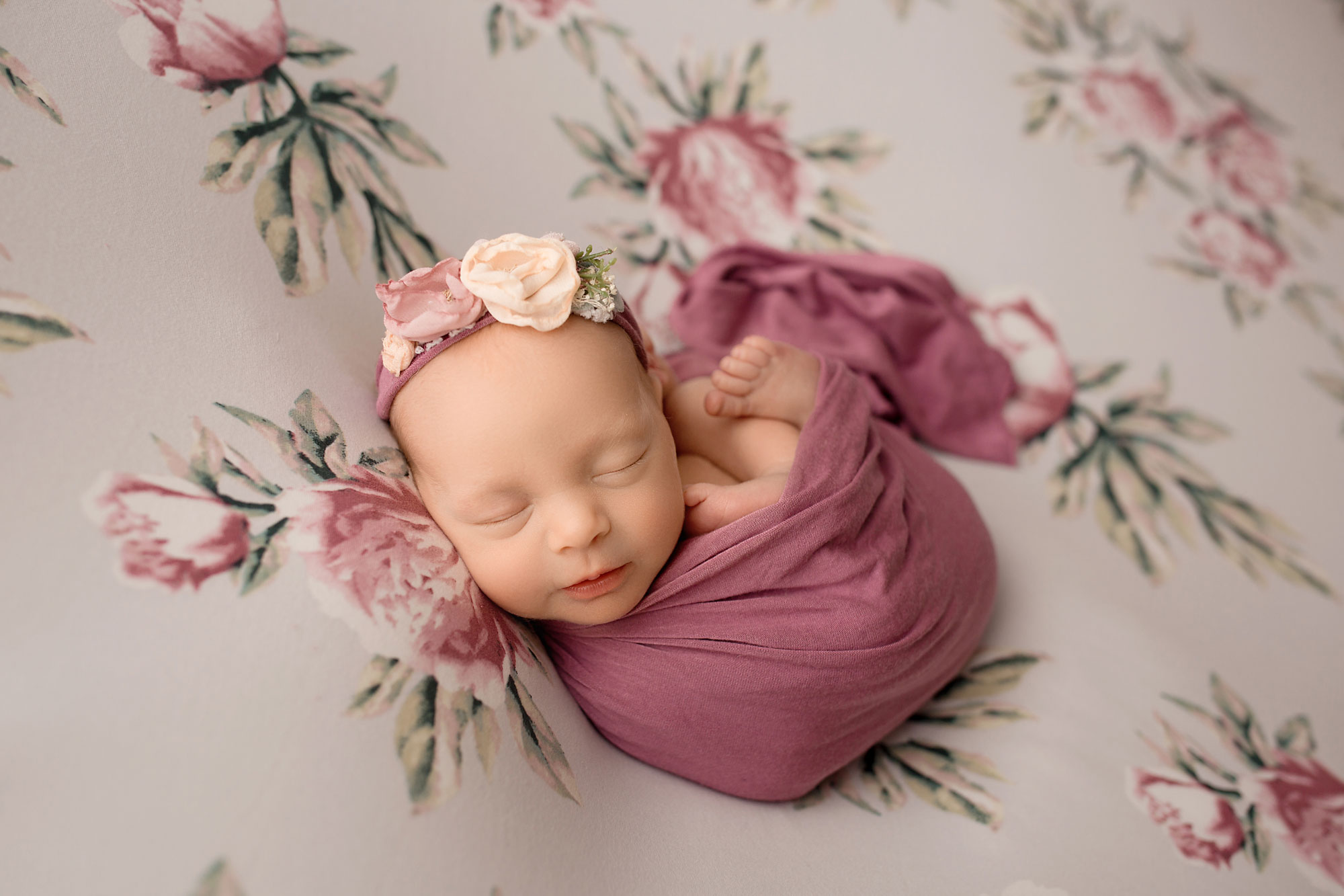 baby girl sleeping n a floral backdrop wrapped posing newborn photo session nj