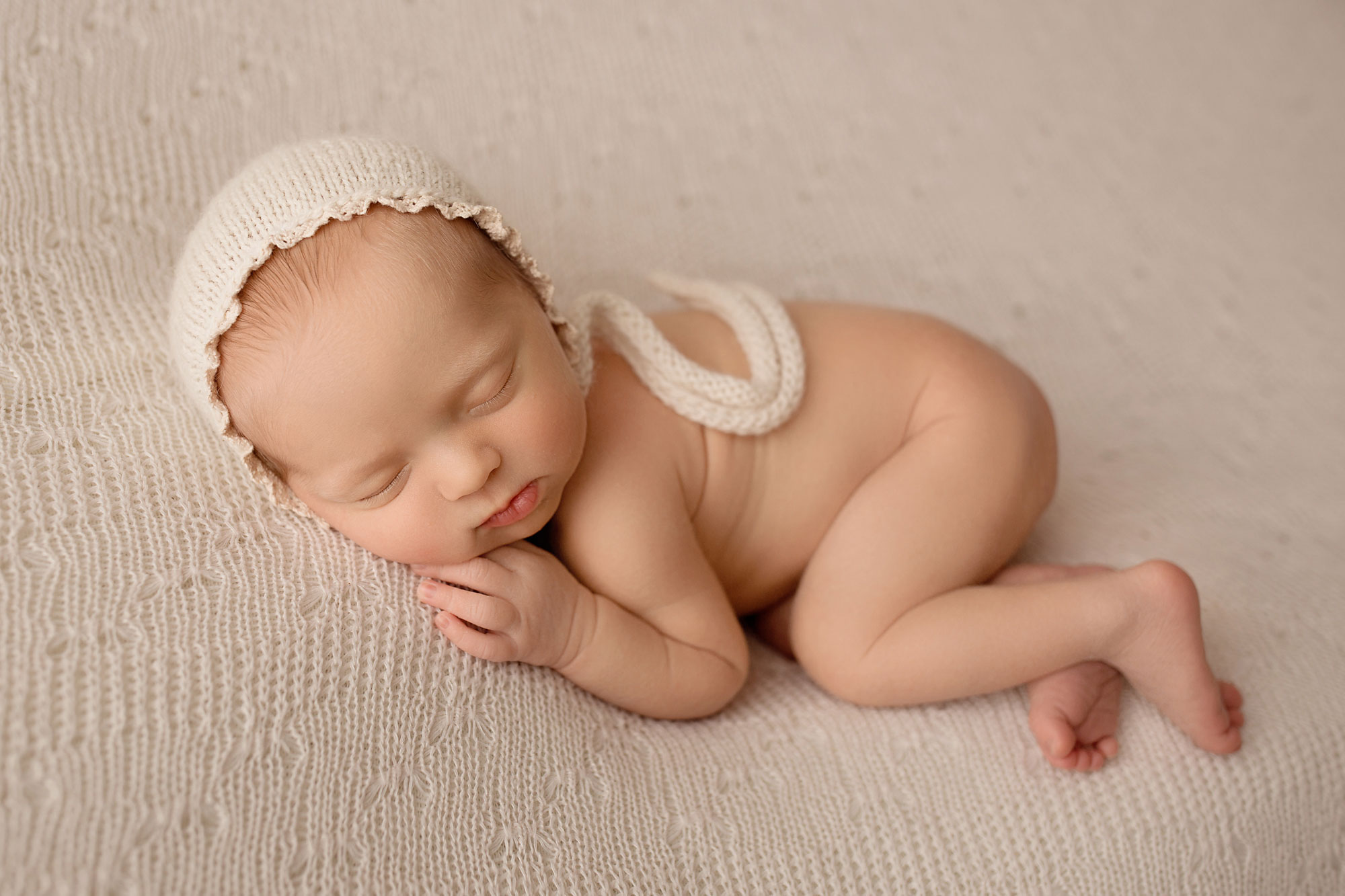 neutral newborn baby girl photo sleeping on a beanbag, vanilla color 