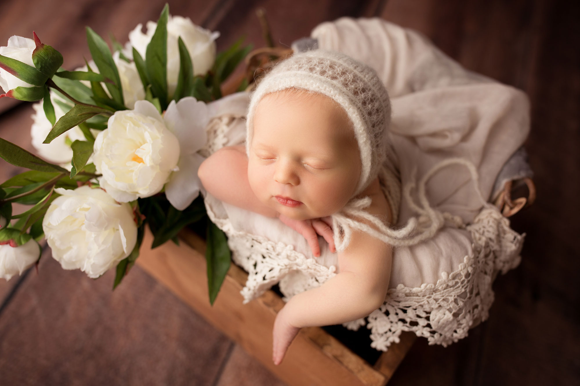 baby girl posed in a bucket with flowers newborn posing in props