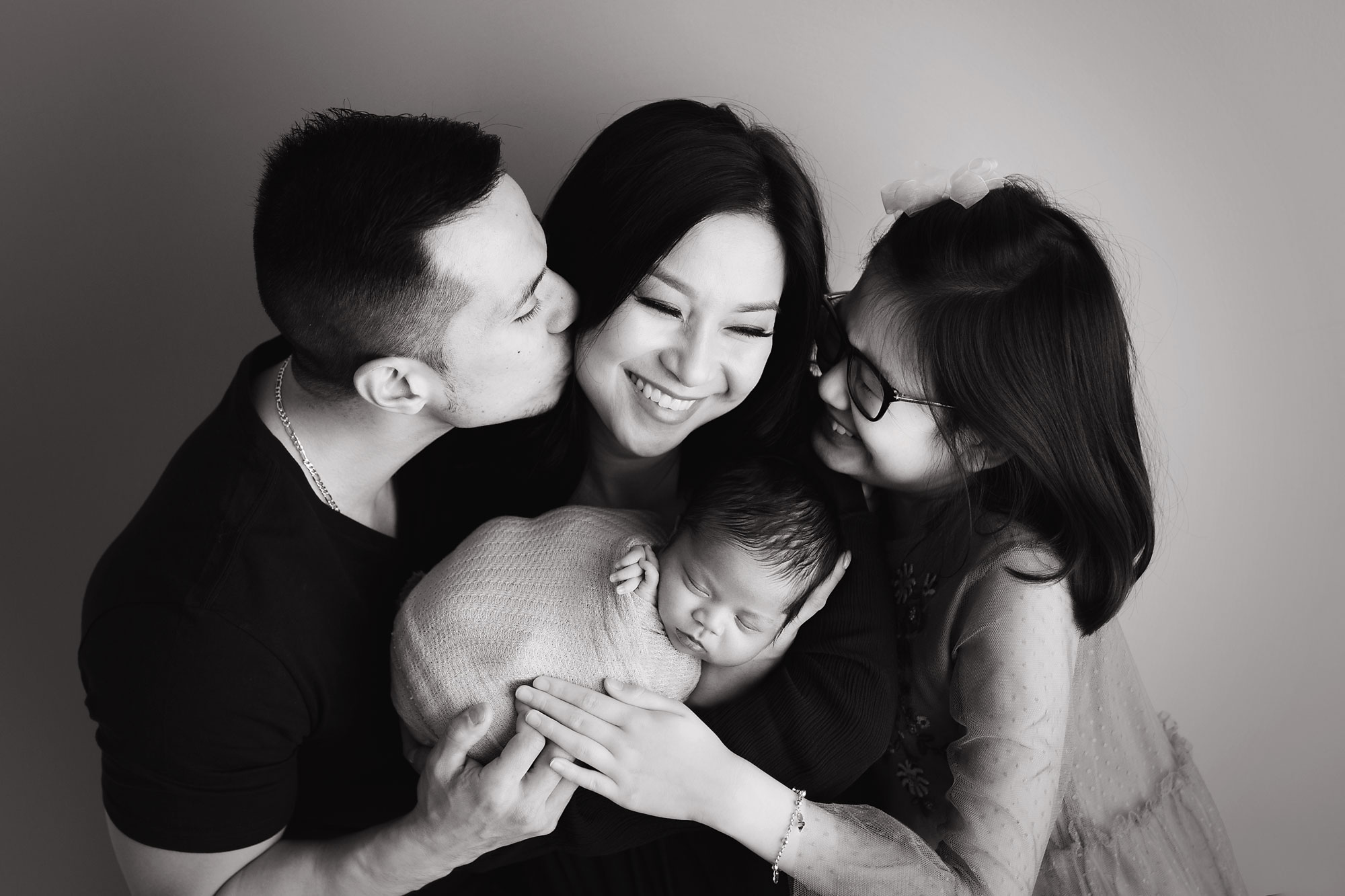family and newborn photo session new jersey baby in moms arms with dad and big sister hugging