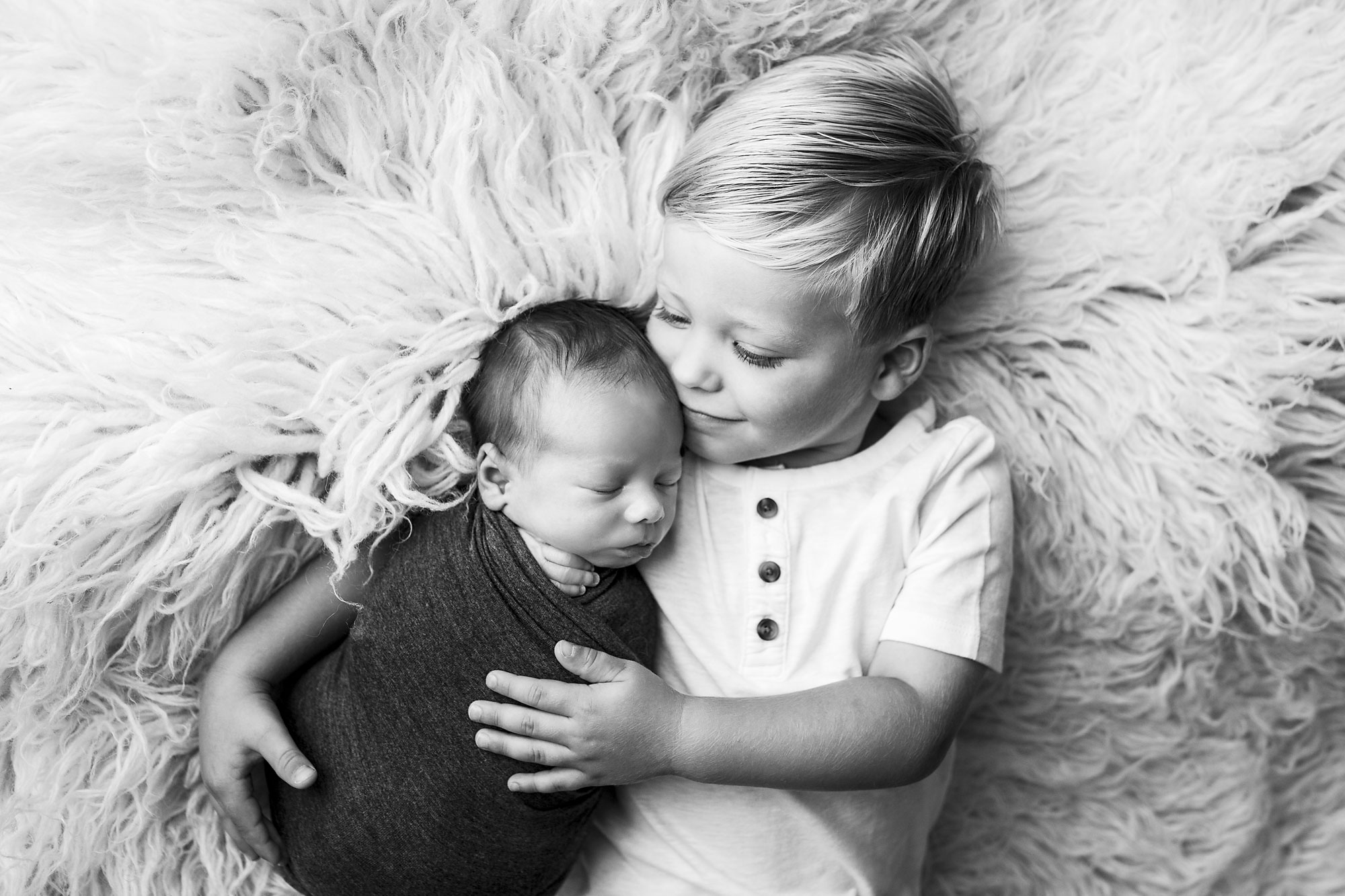 baby and child photographs near me, black and white image of little boy cuddling baby brother