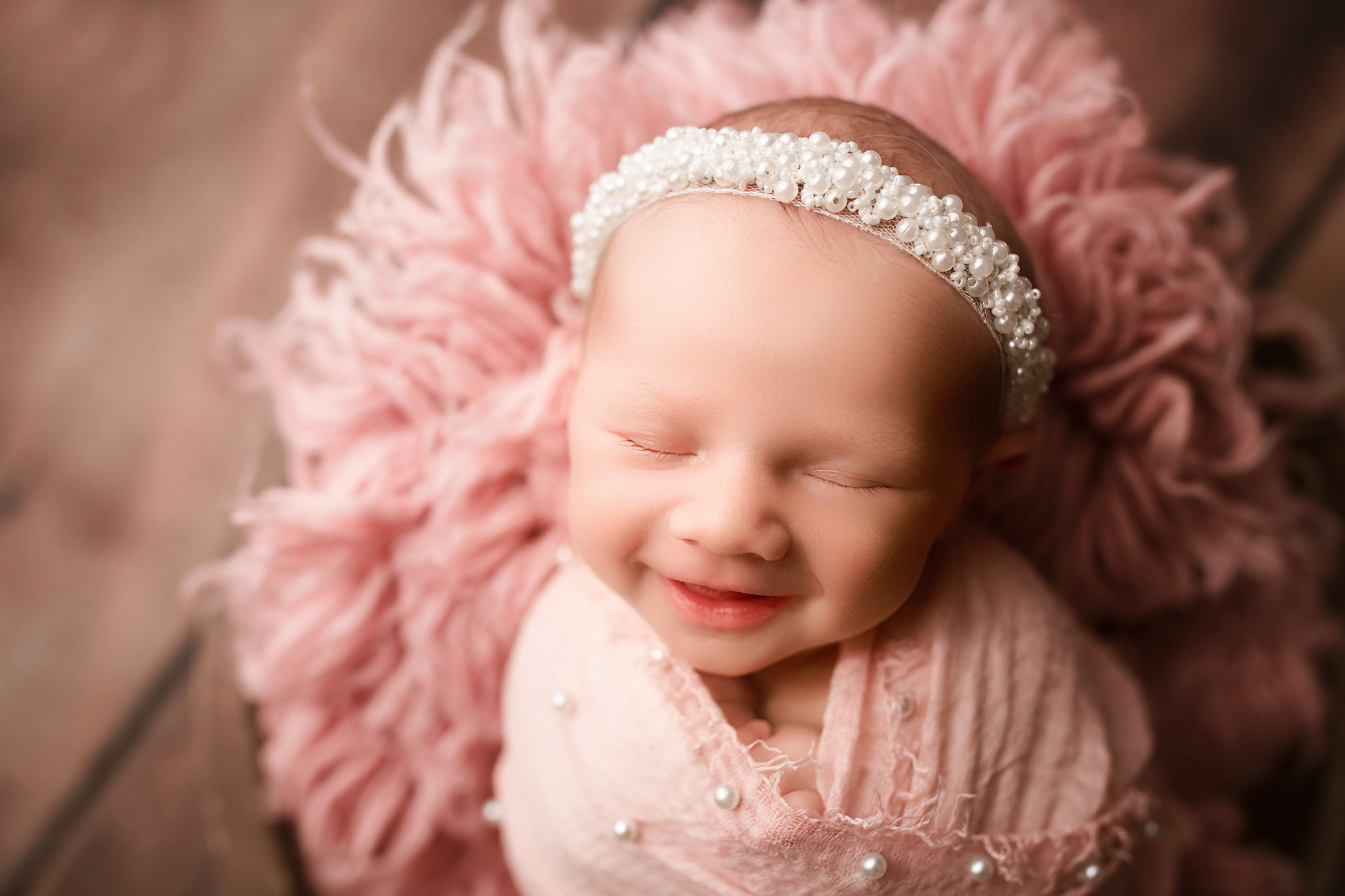 profession newborn pictures nj, smiling baby girl with pink swaddle and pearl headband