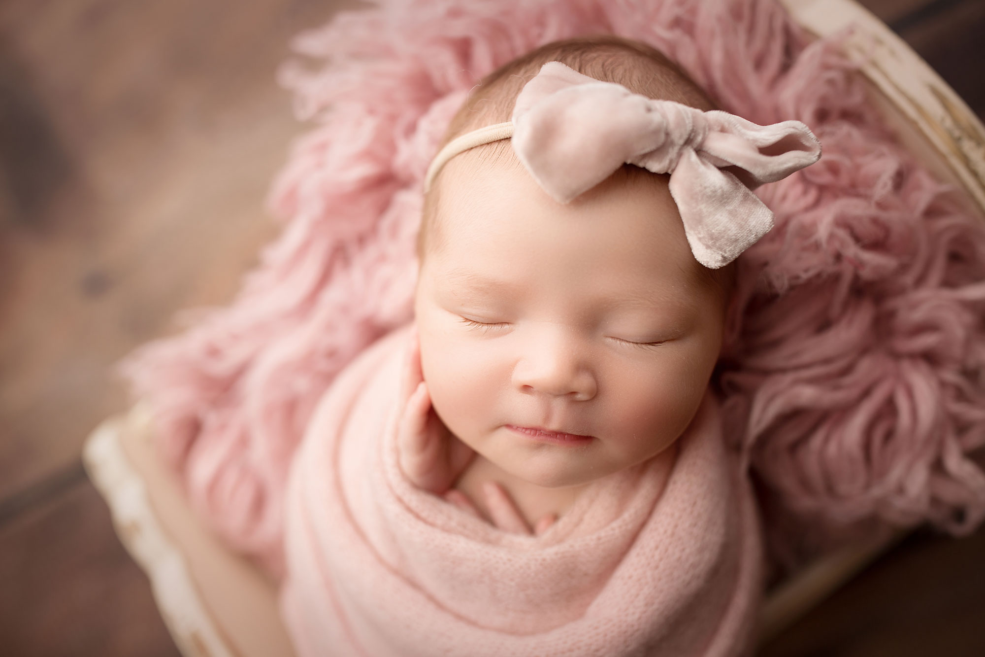 professional newborn baby photo session near me, baby girl in pink swaddle and bow