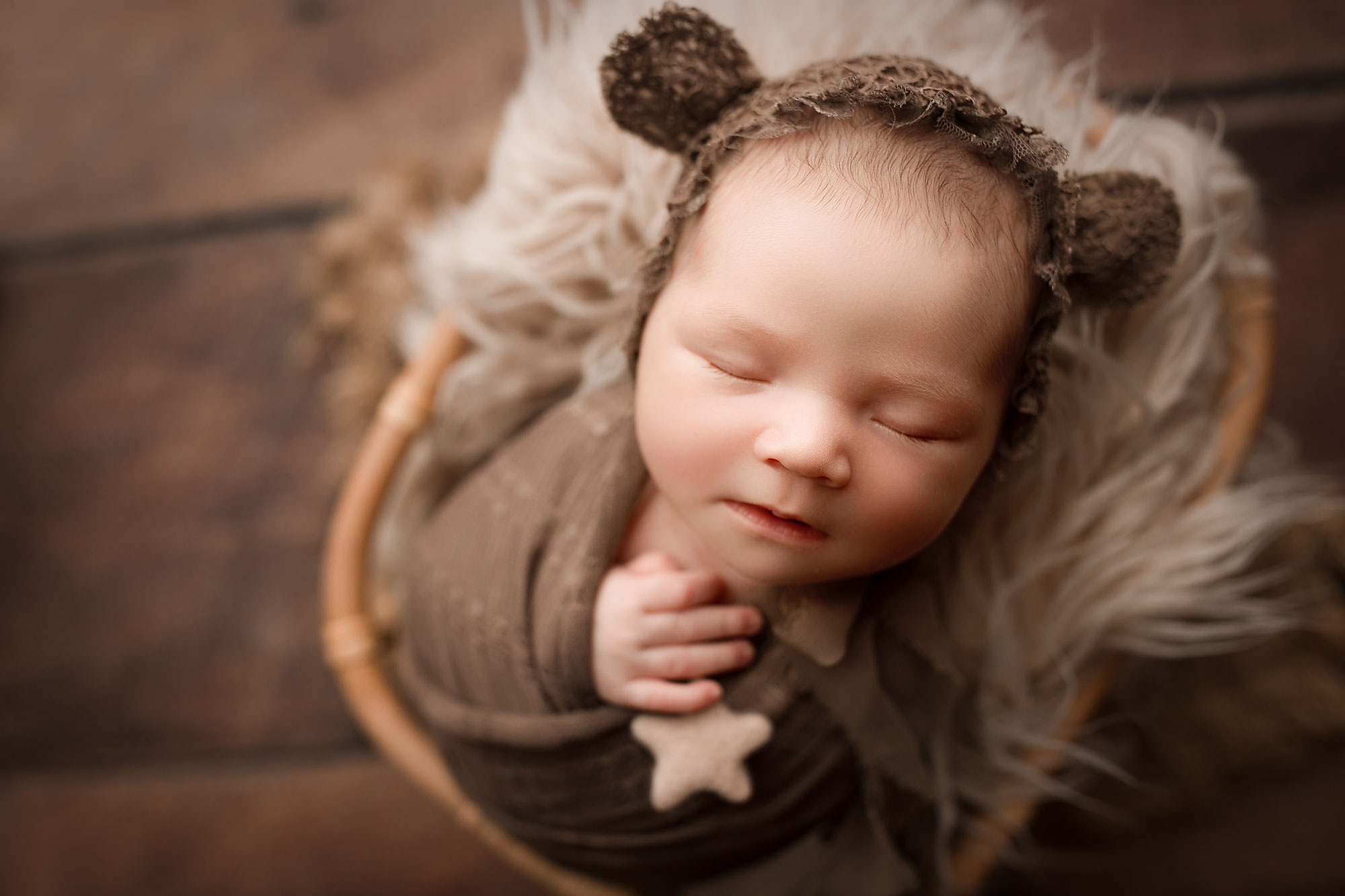woodland theme newborn pictures, baby in brown swaddle and bear cap