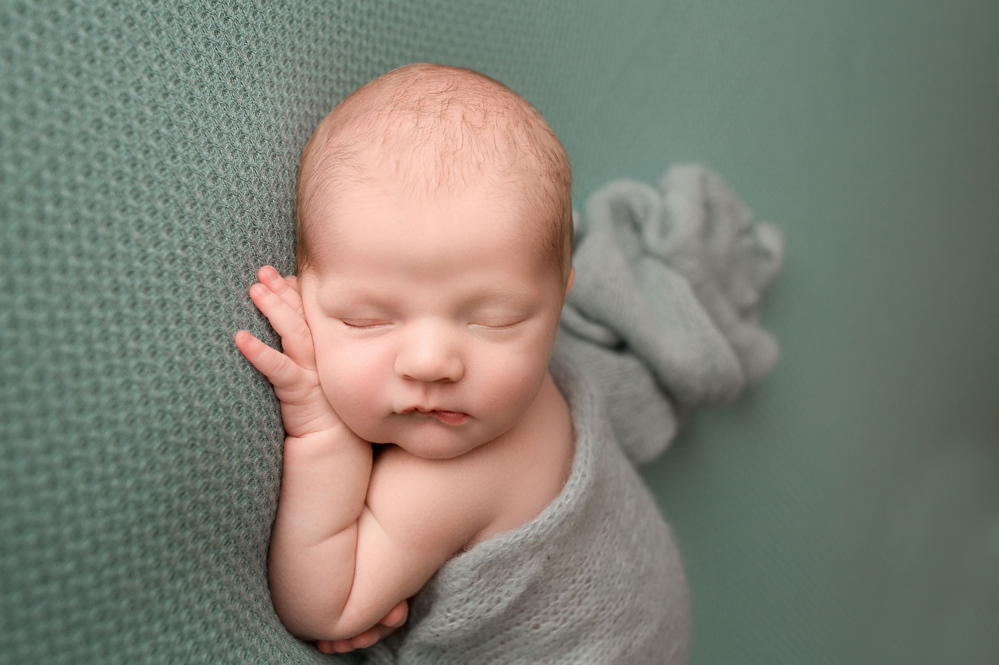 newborn photography session flemington nj, baby boy asleep on teal fabric with soft wrap