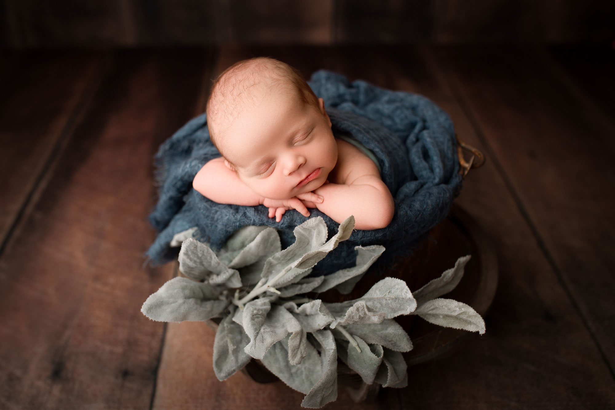 baby boy newborn pictures nj, baby sleeping in bucket with blue blanket against wooden backdrop