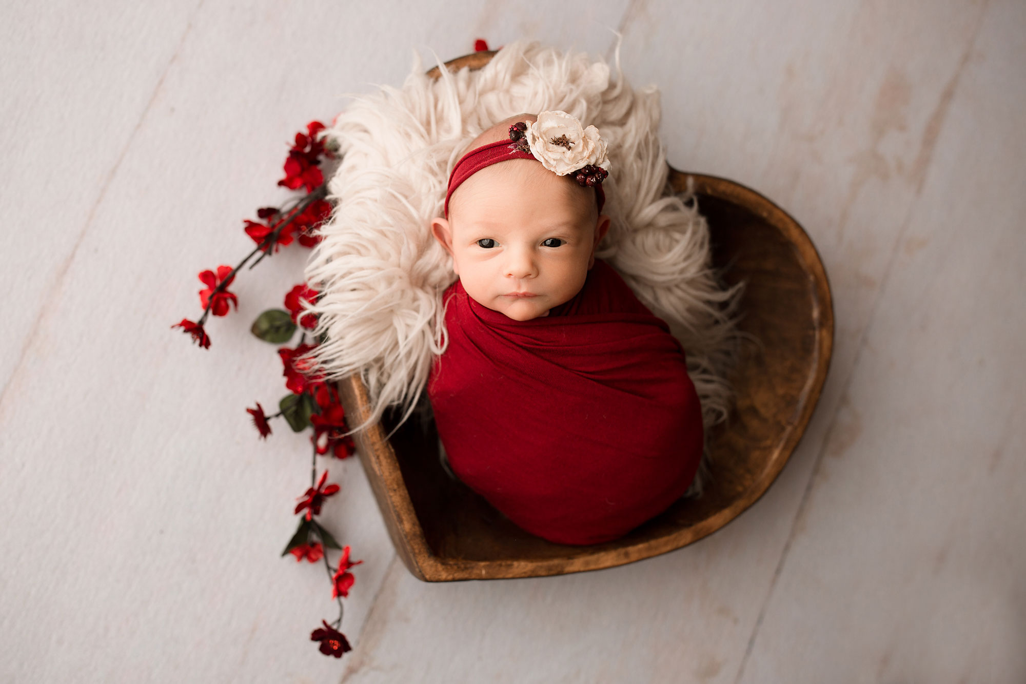 professional nj newborn photographer, wakeful baby girl in wooden heart bowl with red wrap and flowers