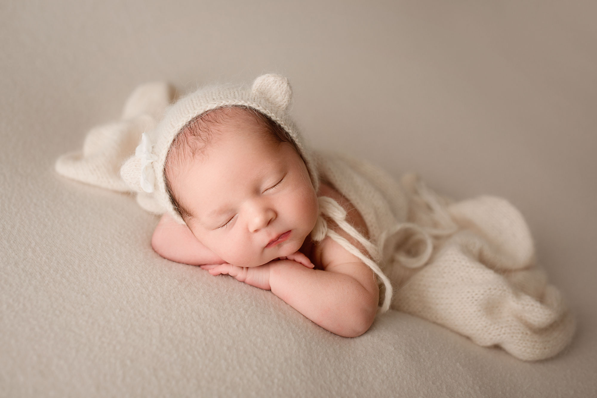 studio newborn photography near me, sleeping baby wearing knit white bear cap and wrapped in white blanket