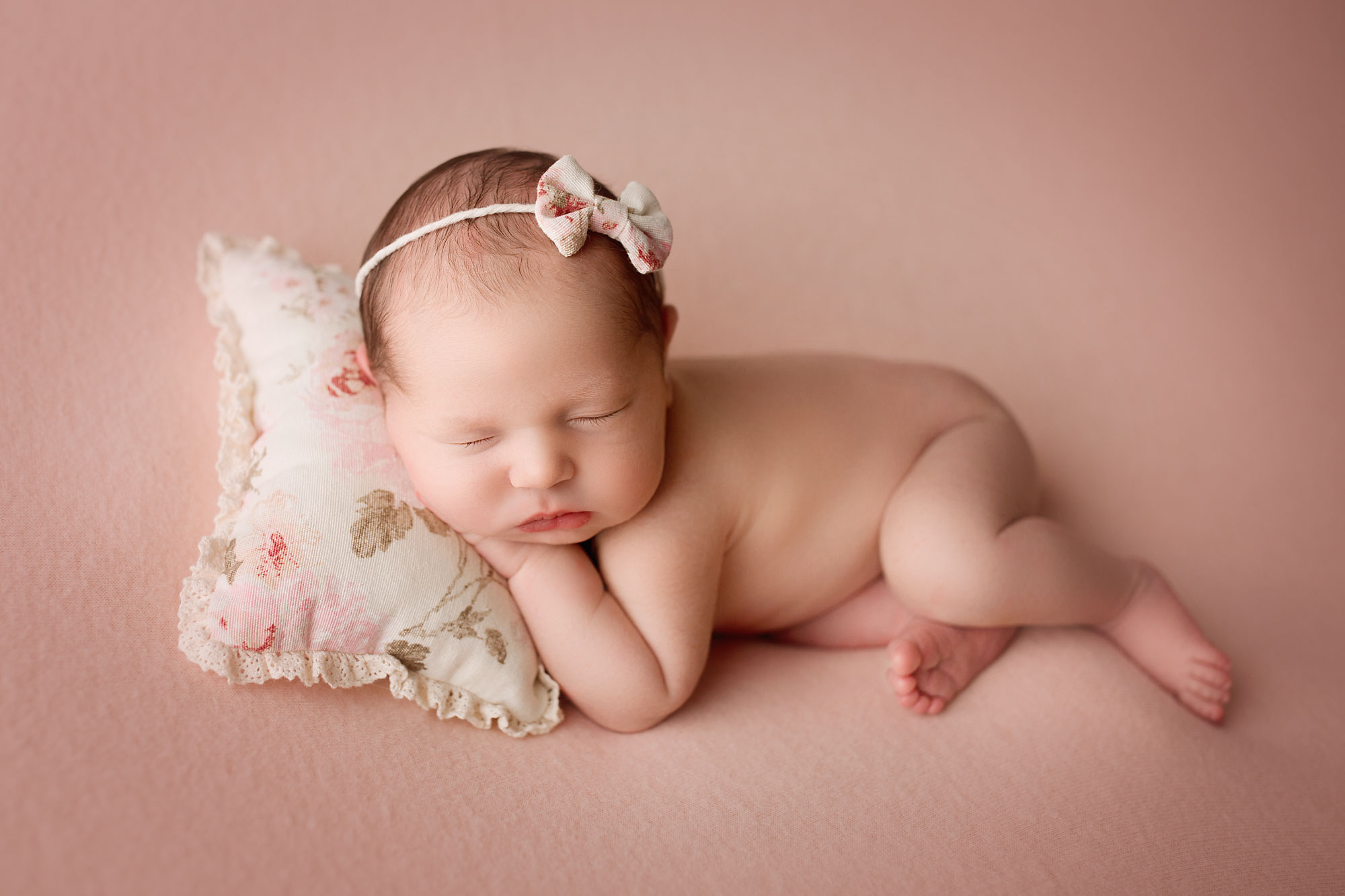 beautiful newborn photography nj, baby girl asleep on floral pillow with matching headband
