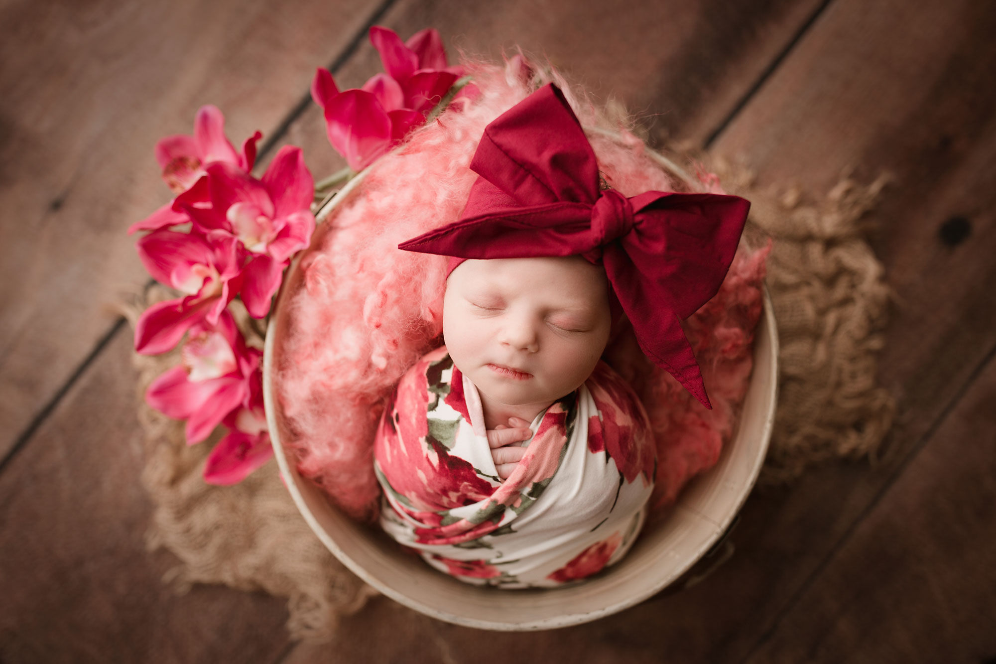 baby portrait photography, infant girl in floral swaddle and bow, asleep in bucket with fur and flowers