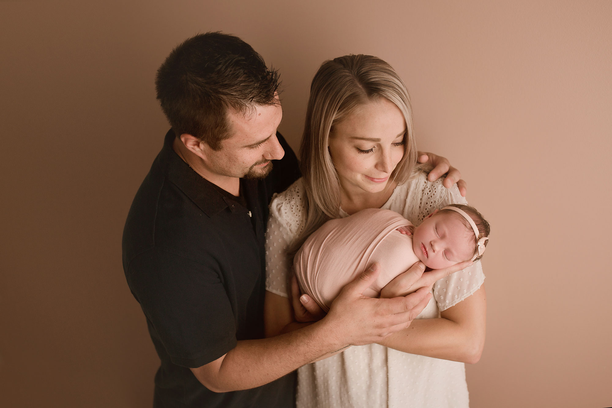 newborn and family photographer near me, dad with arm around mom while mom holds newborn daughter