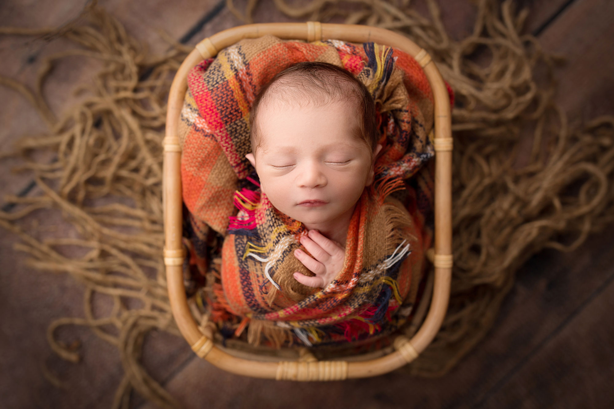 professional baby photos near me, baby in basket wrapped in colorful plaid blanket