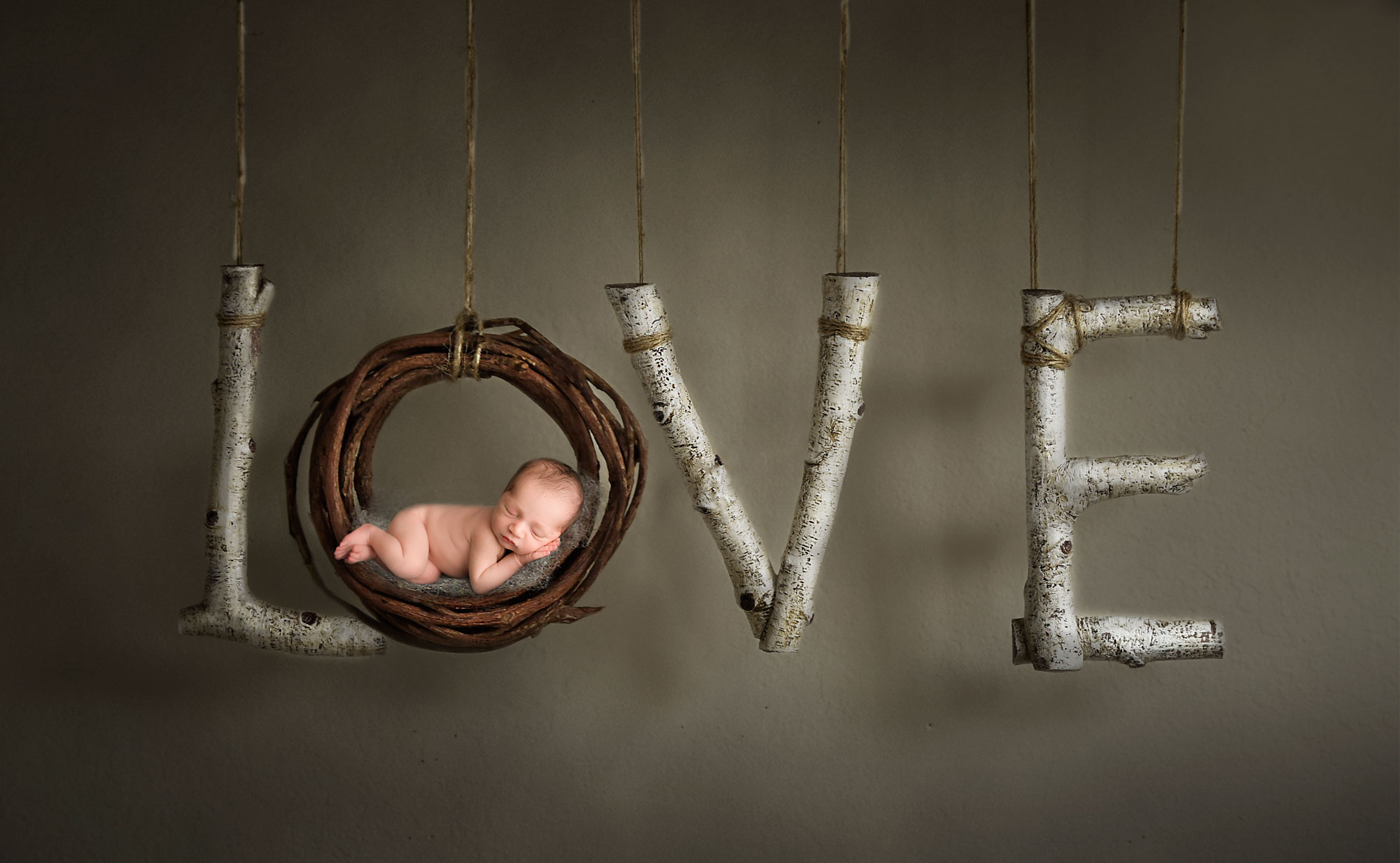 creative baby photography, naked baby asleep in wooden wreath "O" in suspended LOVE sign