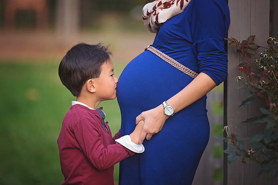 what to wear to an outdoor maternity session , boy kissing mommy belly