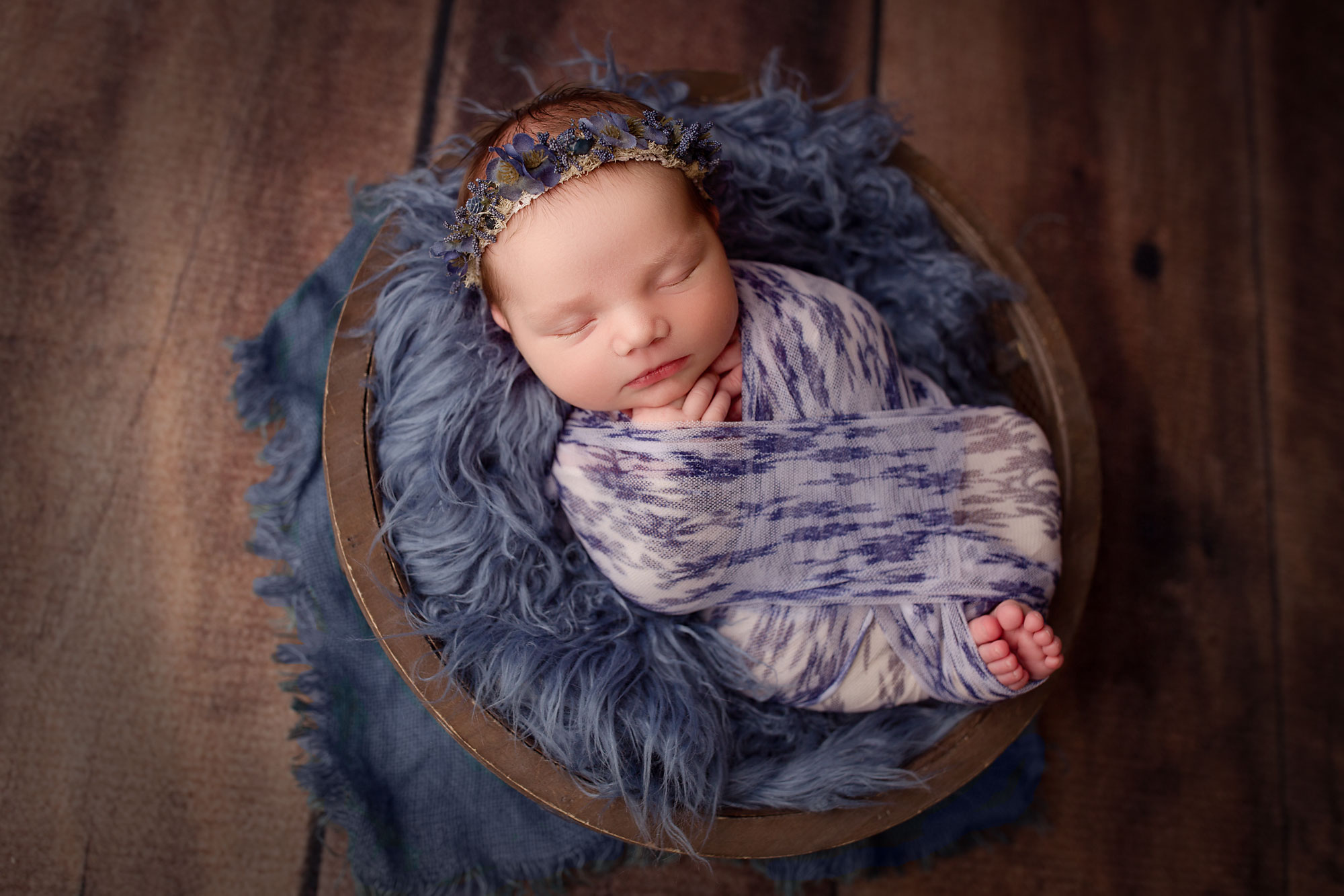 newborn photographer nj, baby girl asleep in bucket with blue fur and swaddle