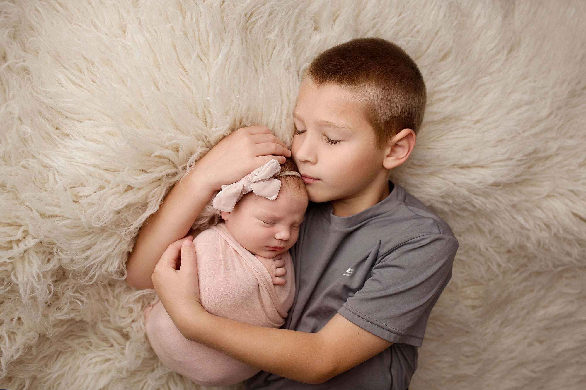 baby and child photographer near me nj, young boy lying on fur rug and snuggling infant sister