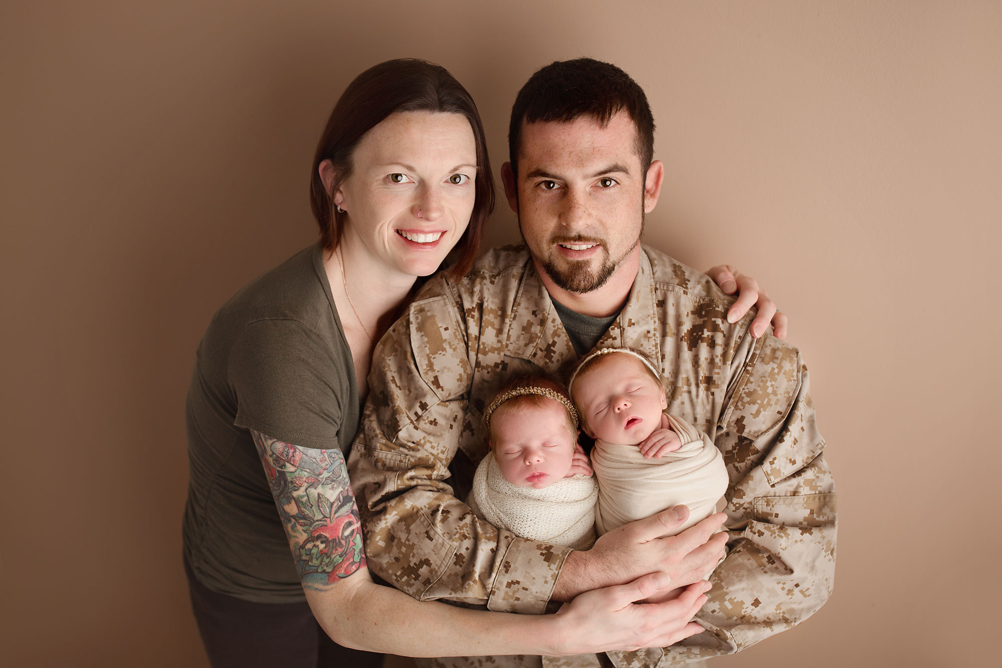 baby and family photographer, parents holding twin girls against neutral backdrop