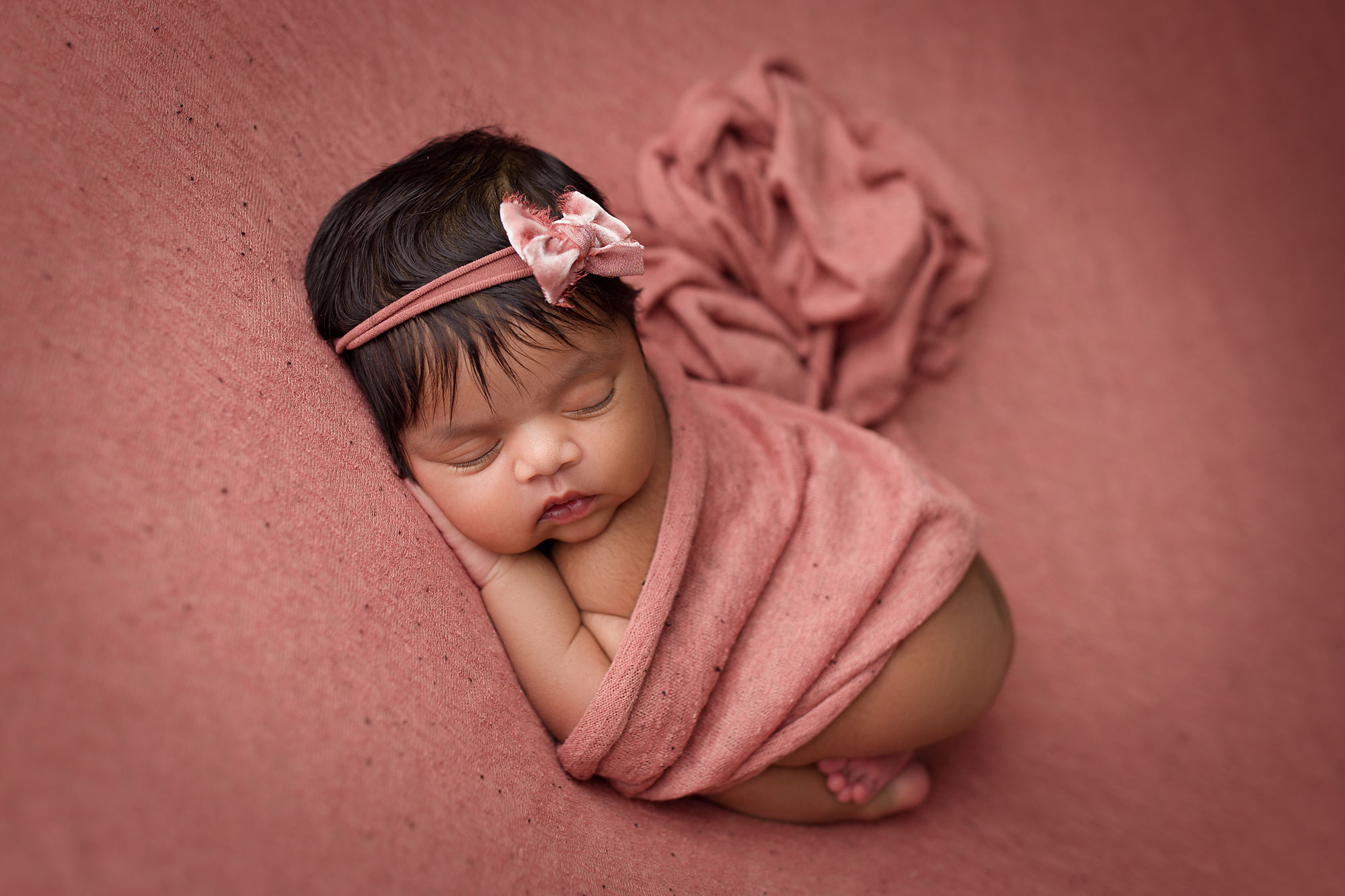 new jersey newborn photographer, baby girl sleeping on pink background with matching wrap and bow