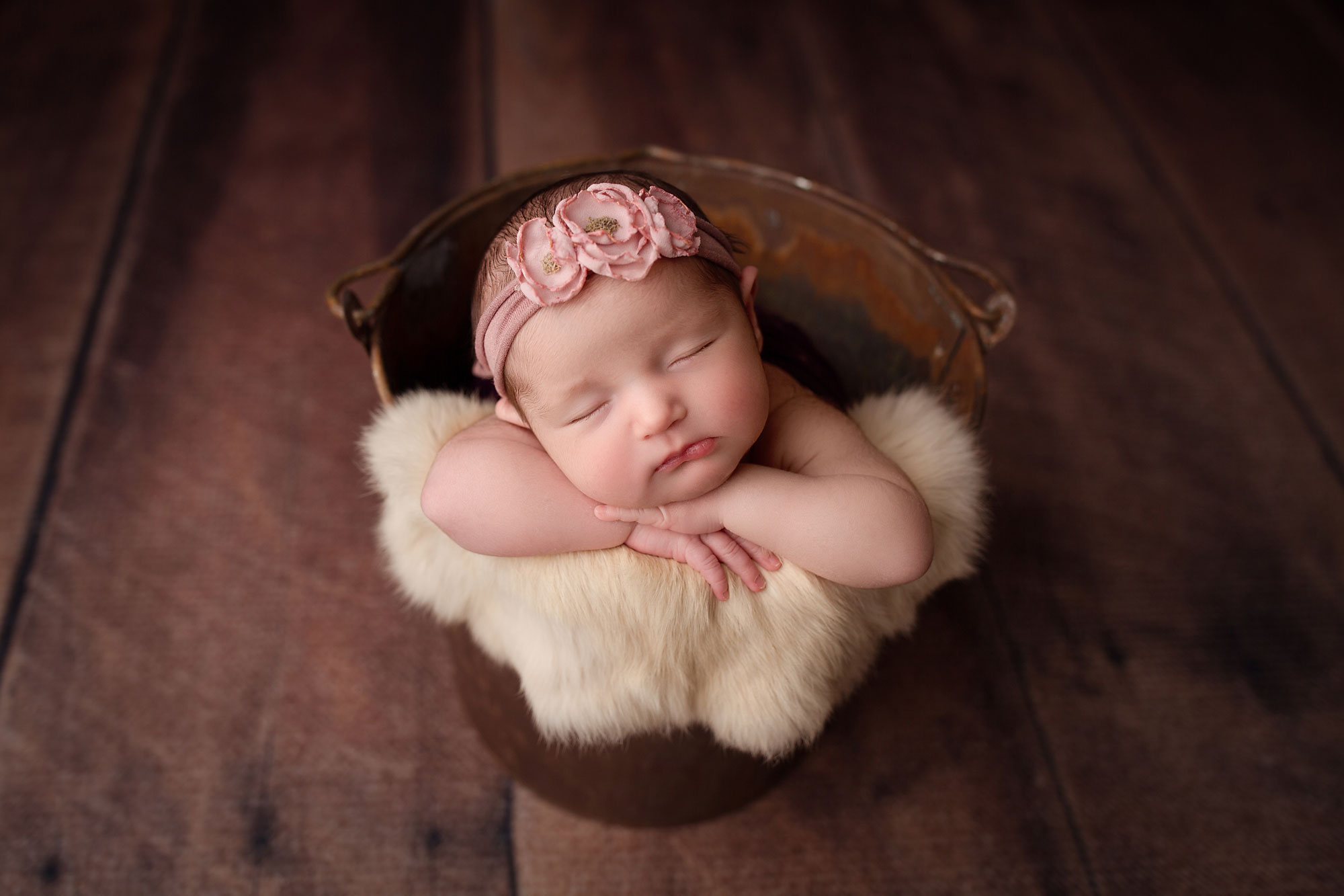 baby girl in photo by hudson county nj newborn photographer, baby girl sleeping in bucket with fur and flower headband