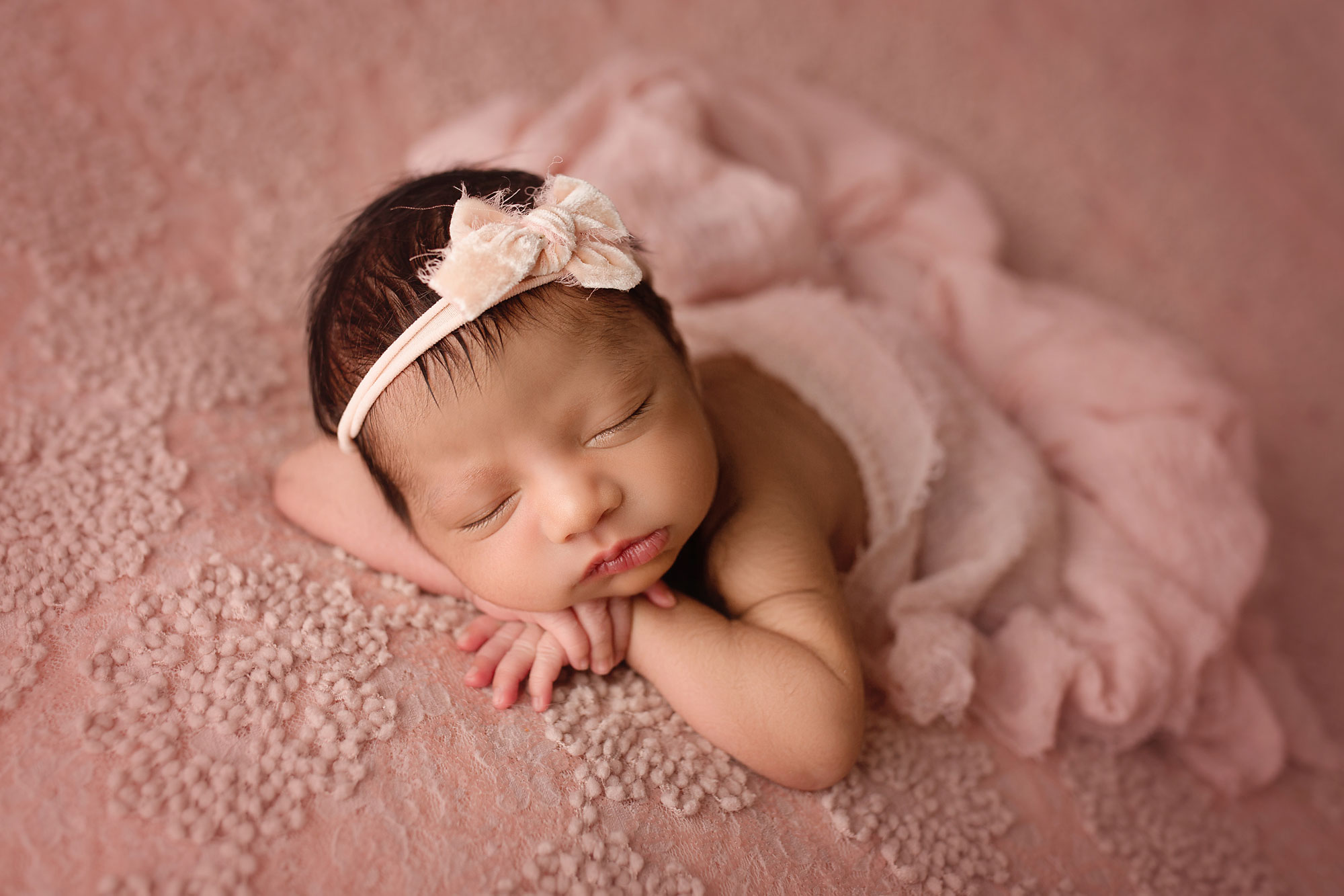 middlesex county newborn photography, baby girl wrapped in pink blanket with bow in hair sleeping on textured pink beanbag