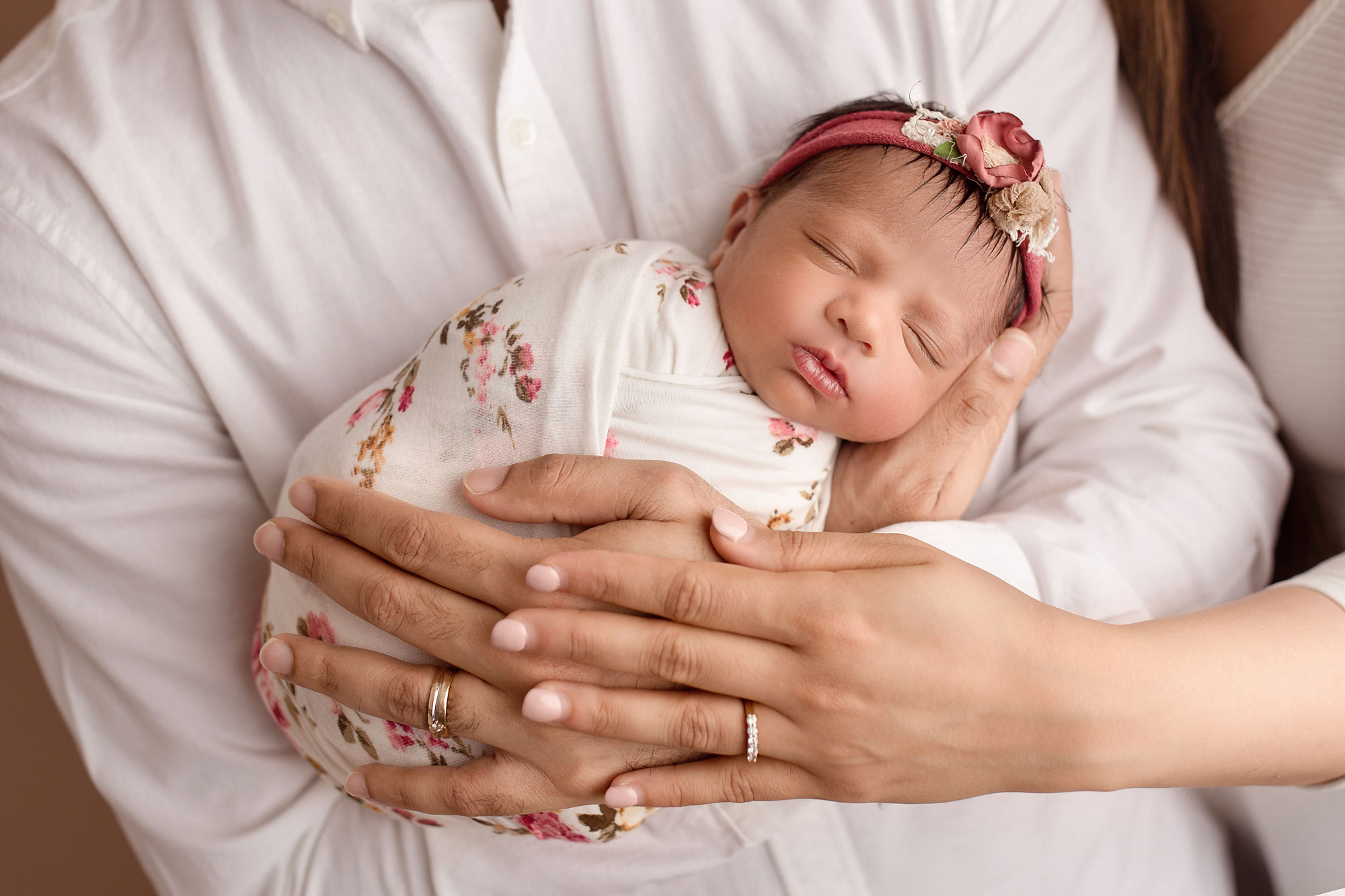 professional baby pictures nj, baby girl in floral wrap sleeping in parents' arms