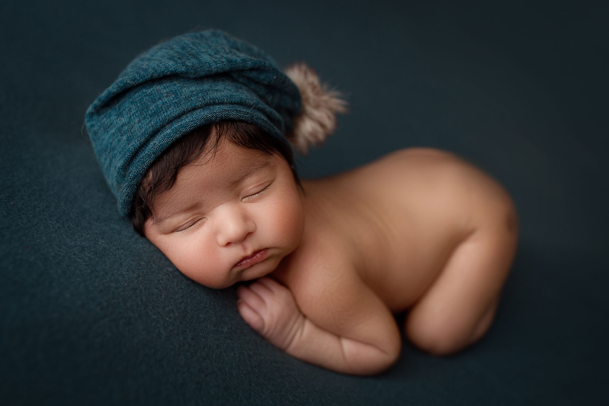 nj baby pictures, sleeping baby boy with blue cap against dark blue background