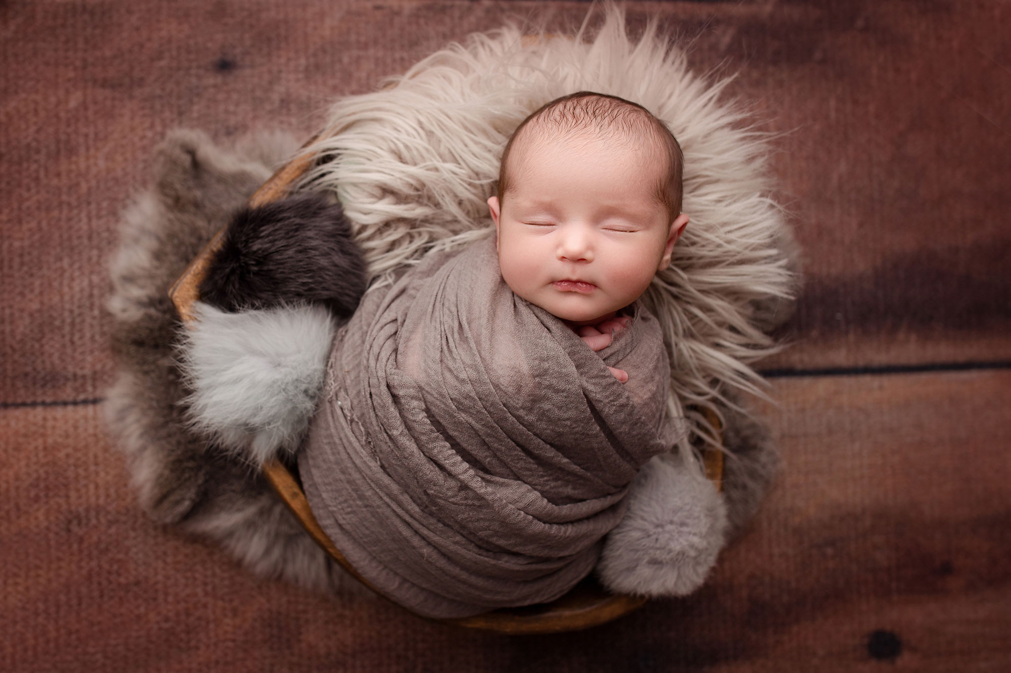 hudson county newborn photographer, baby in gray wrap with gray fur on wood background