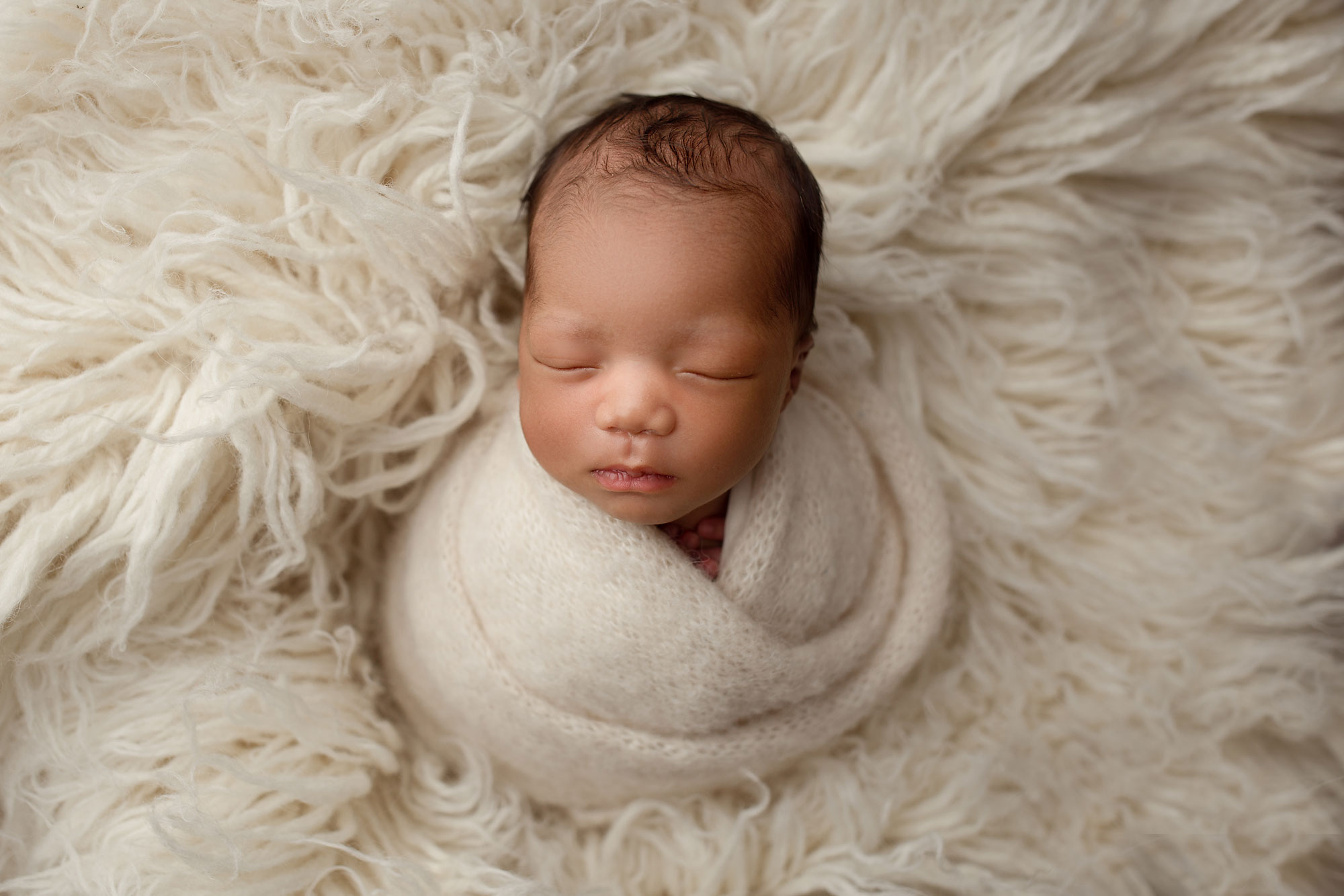 newborn photographer pennsylvania, swaddled baby on white fur rug