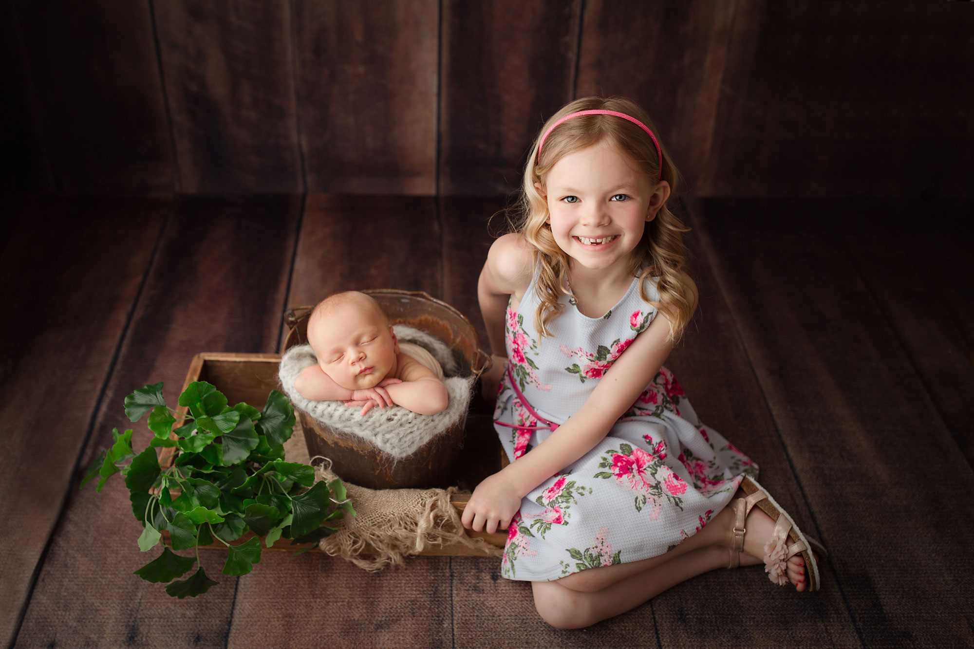 newborn and sibling baby photography pittstown, baby asleep in bucket with sister next to him in flowered dress