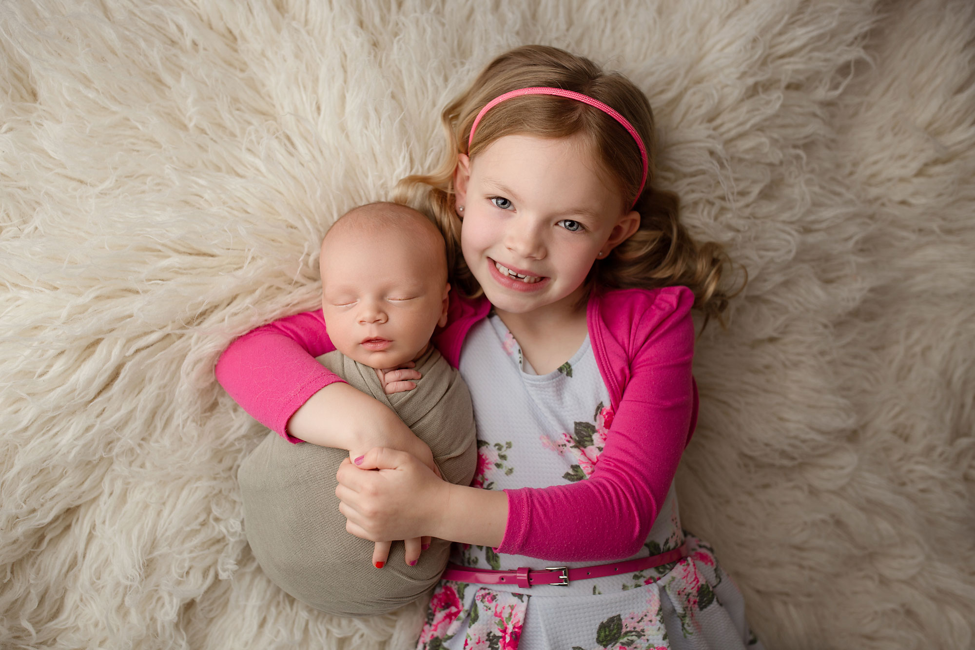 baby and child portraits nj, big sister holding little brother while lying on white rug