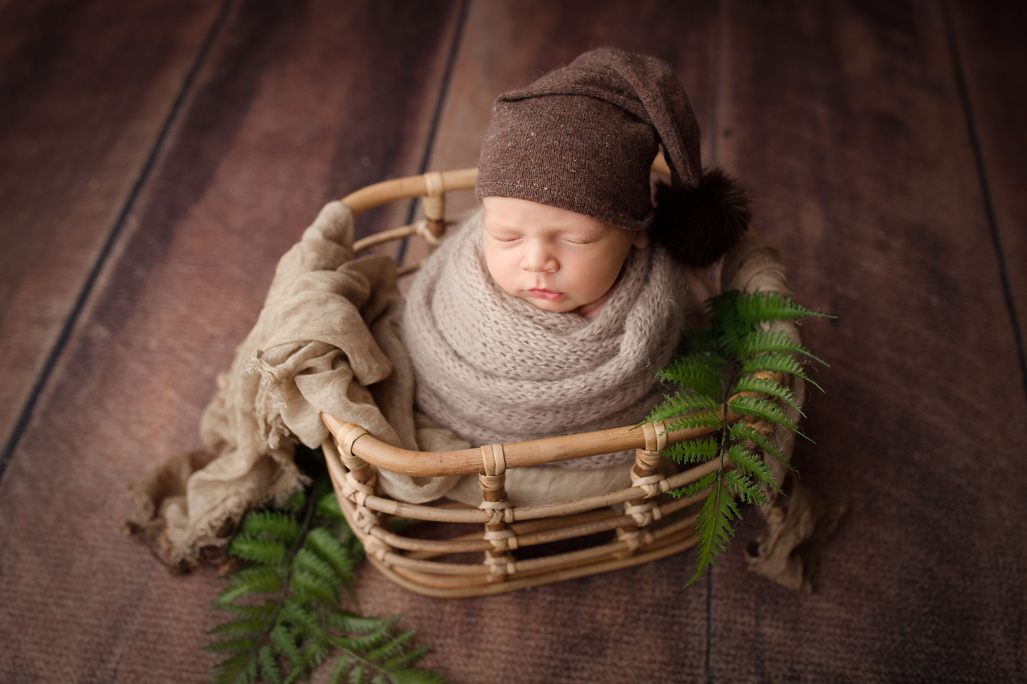 newborn photography near me pittstown, baby swaddled in gray with brown hat sleeping in wicker basket