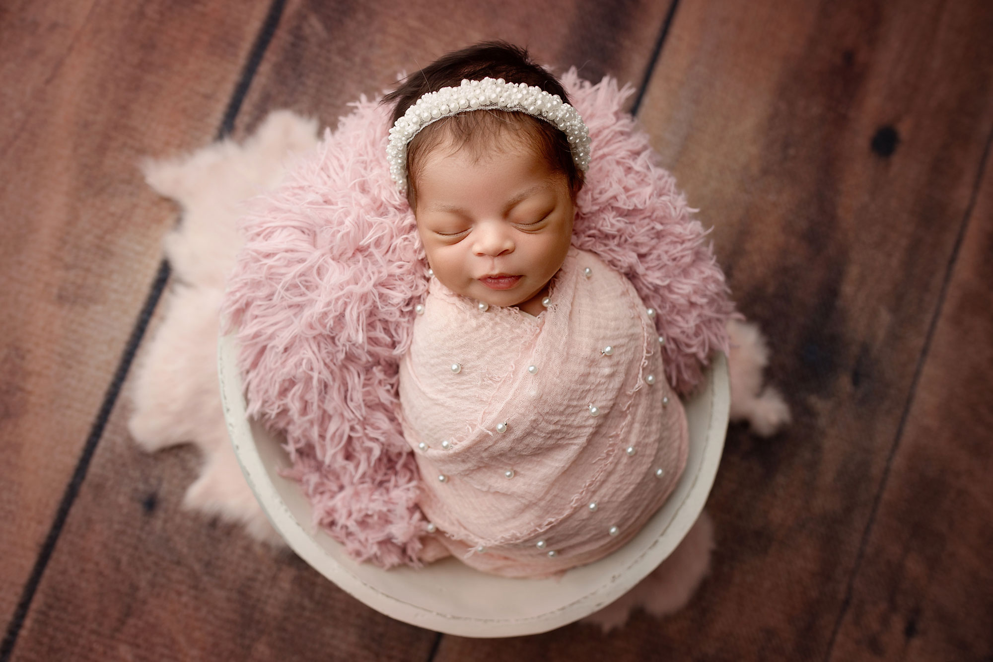 baby pictures near me nj, baby in pale pink swaddle and pearl headband on fur