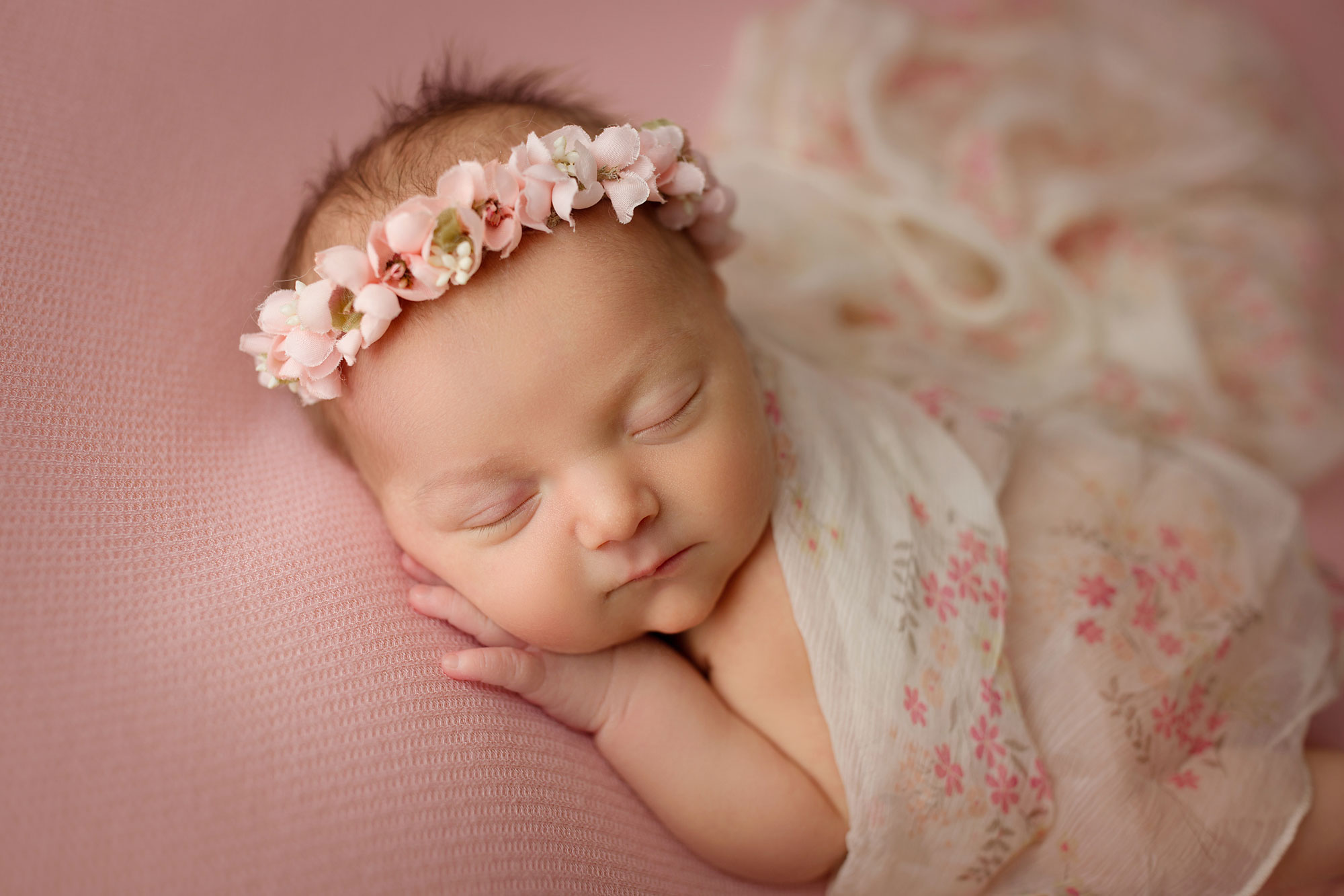 baby girl pictures, infant with floral wrap and headband asleep on pink fabric