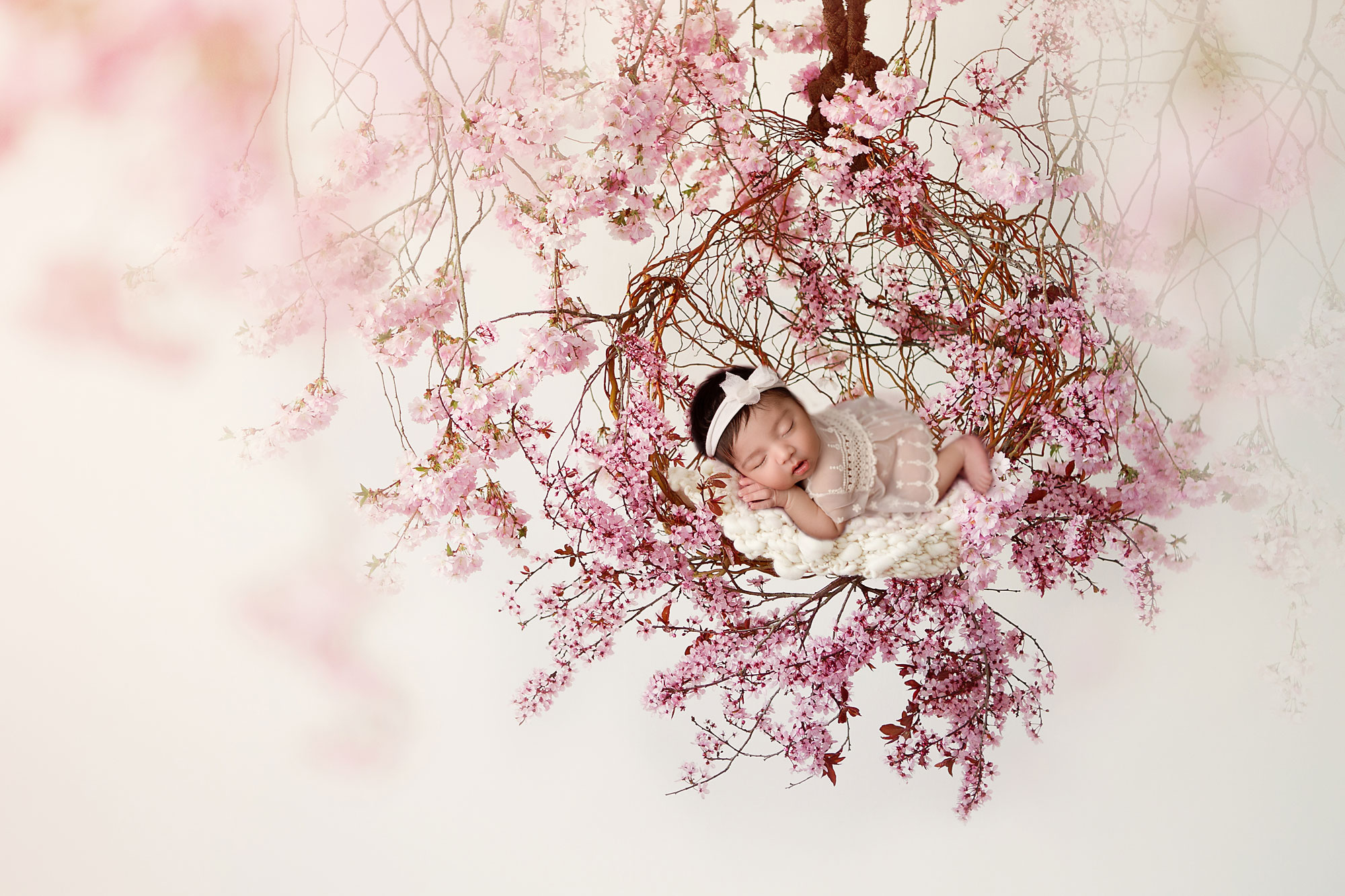 newborn composite images, infant in white asleep on cherry blossom wreath