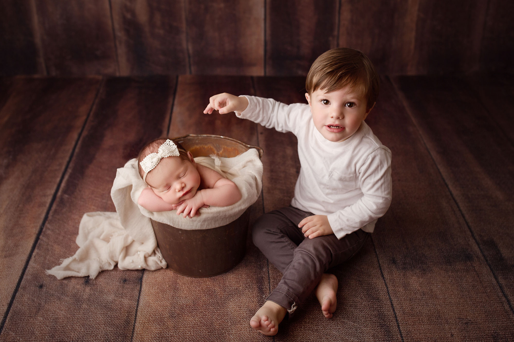 newborn and siblings images near me New Jersey, toddler boy seated on floor next to baby sister