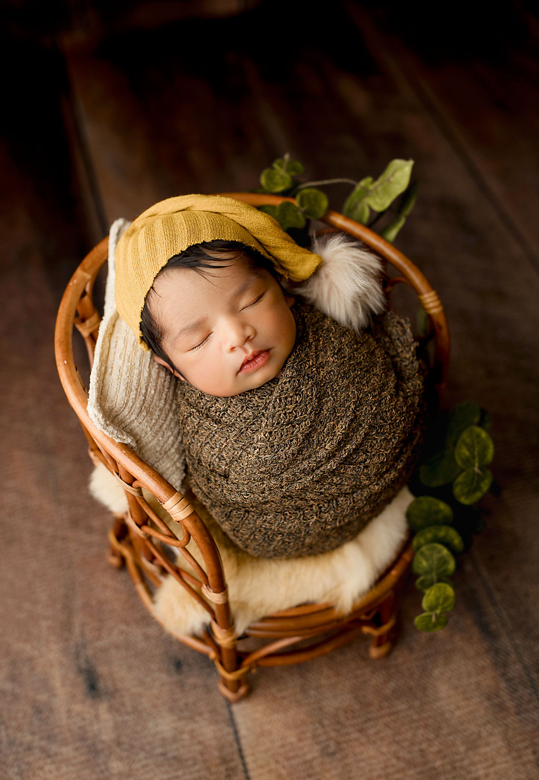 baby boy sleeping ia basket with orange bonnet 