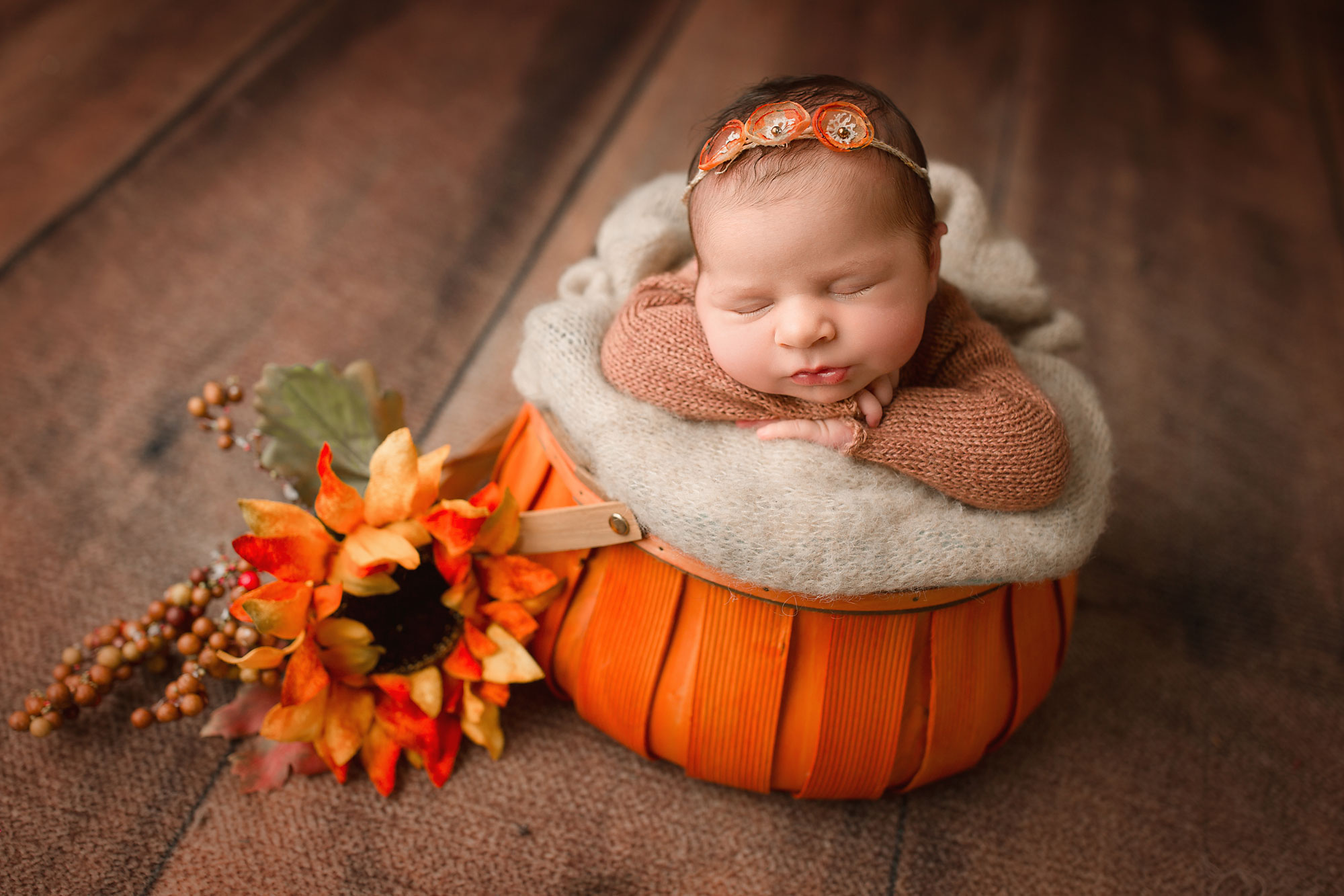 newborn baby girl sleeping in a pumpkin basket 