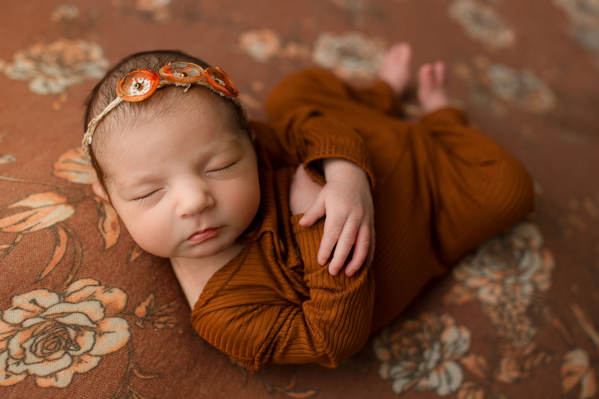 baby girl sleeping on an orange floral drop