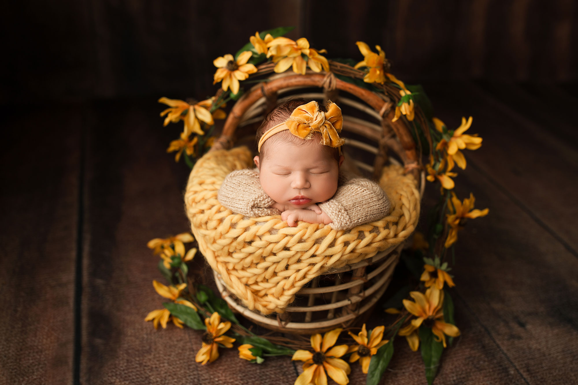newborn baby in a basket with yellow sunflowers