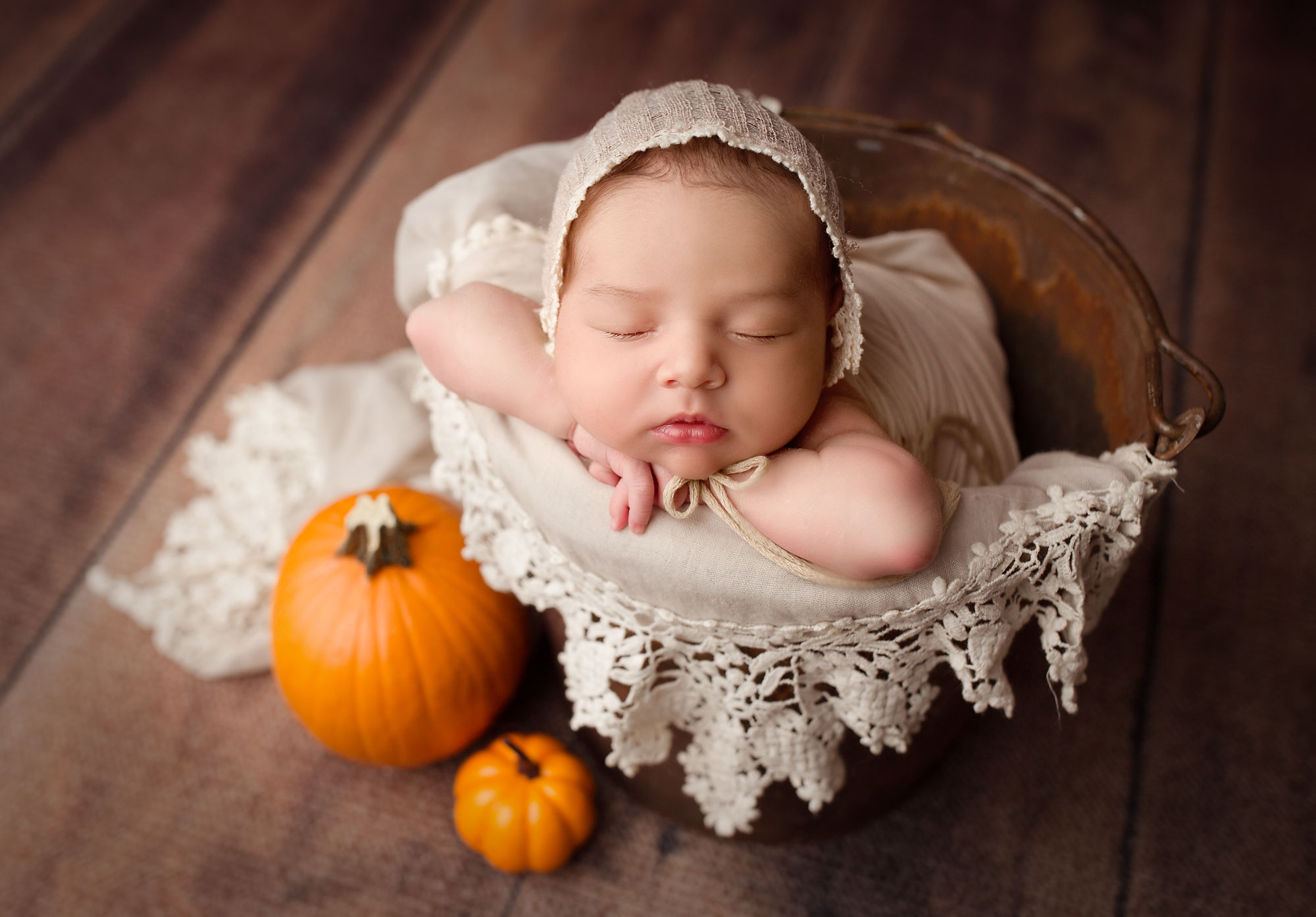 newborn baby girl in a basket with 2 pumpkins 