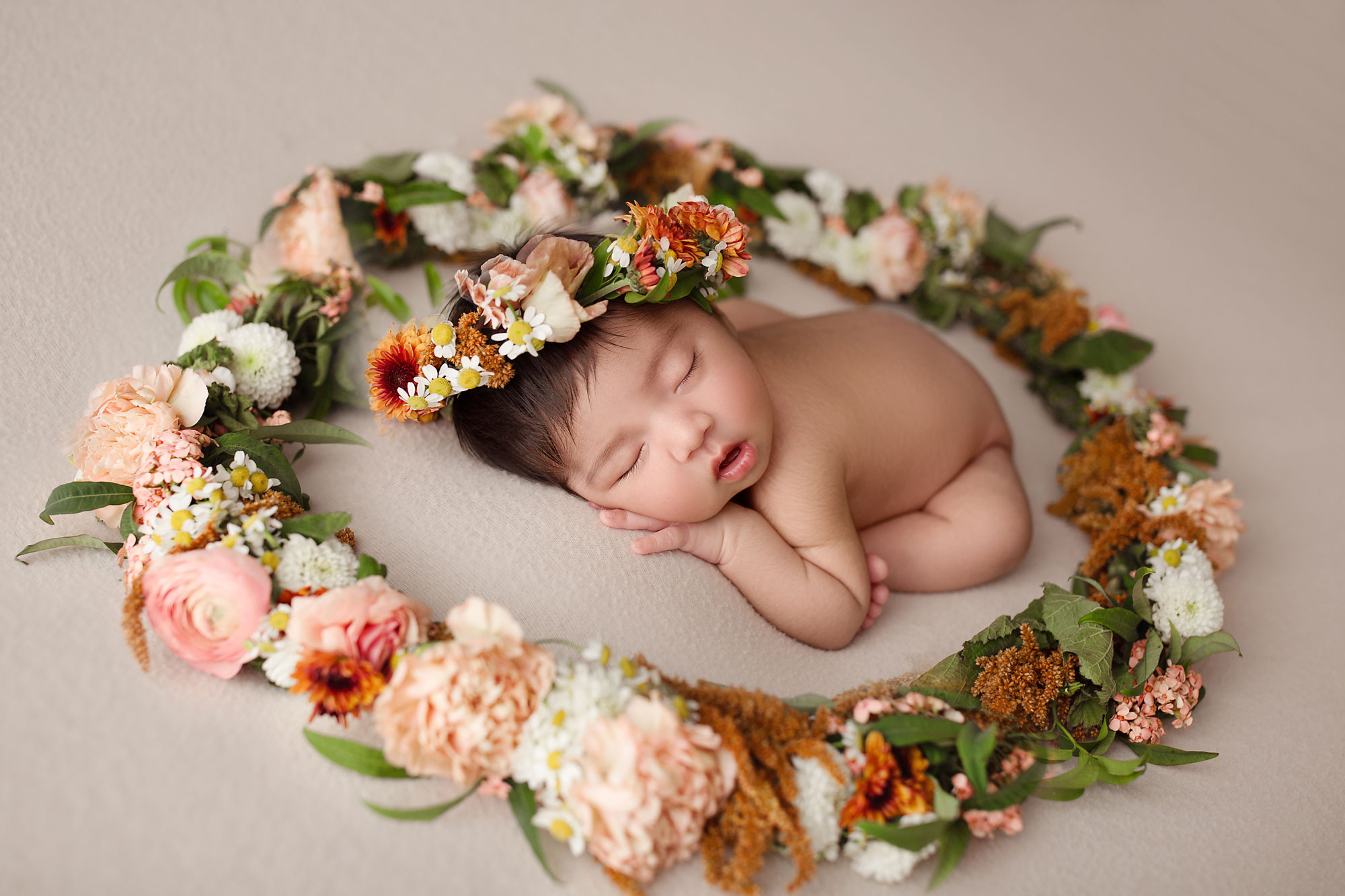 baby girl sleeping on a blanket surrounded by fresh flowers