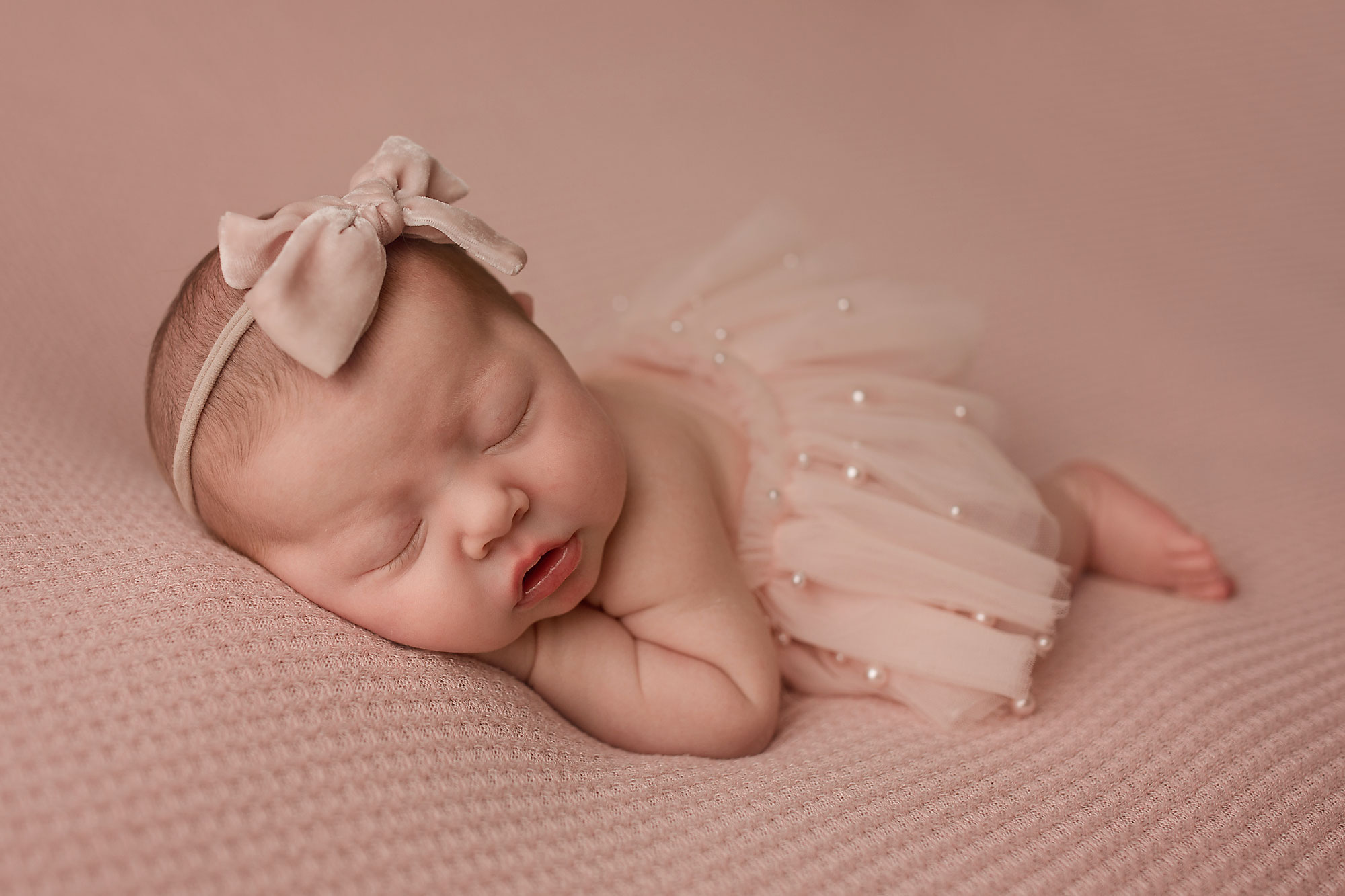 baby sleeping on a pink fabric