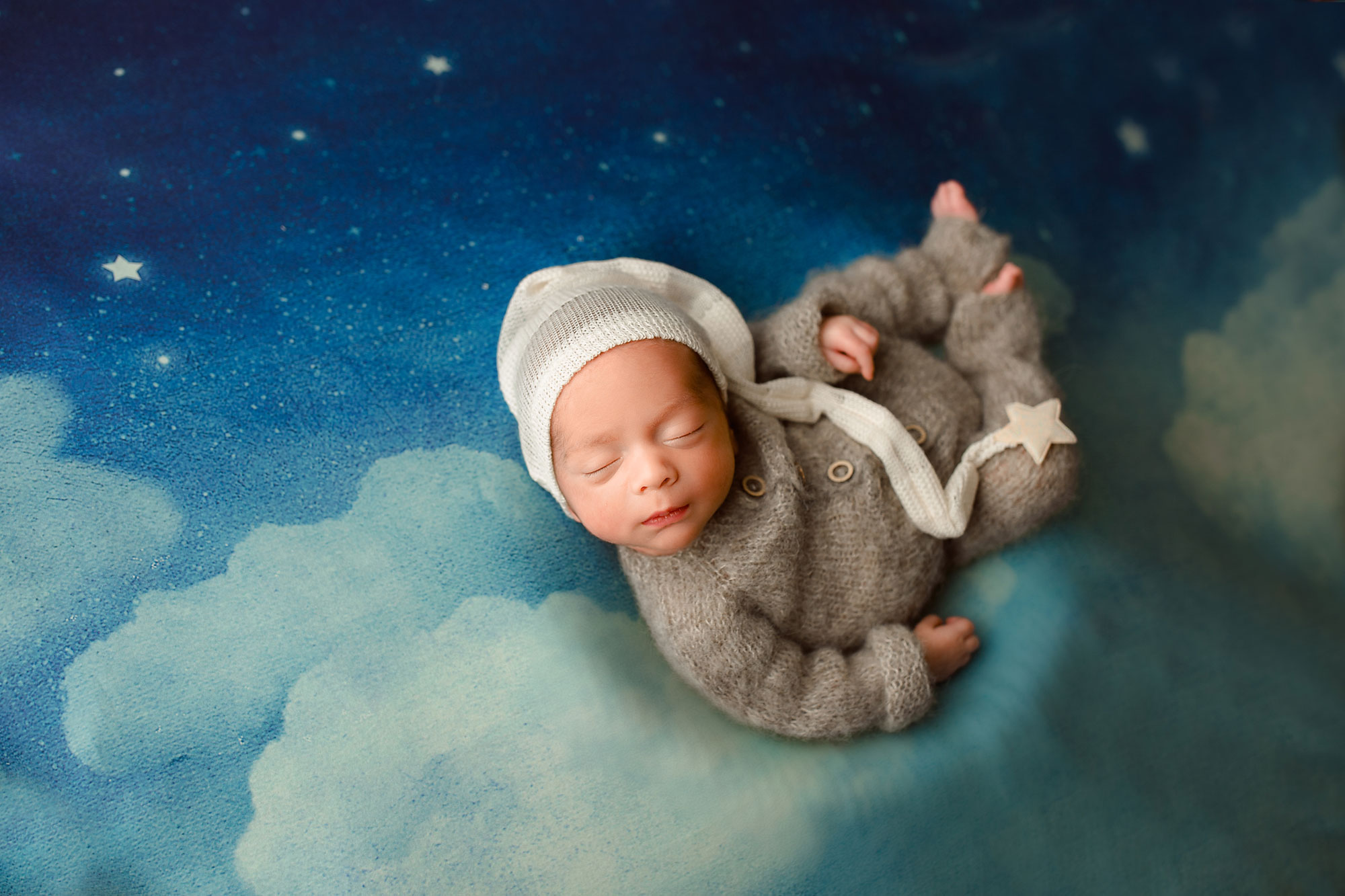 sleepy newborn baby boy on a blanket with clouds