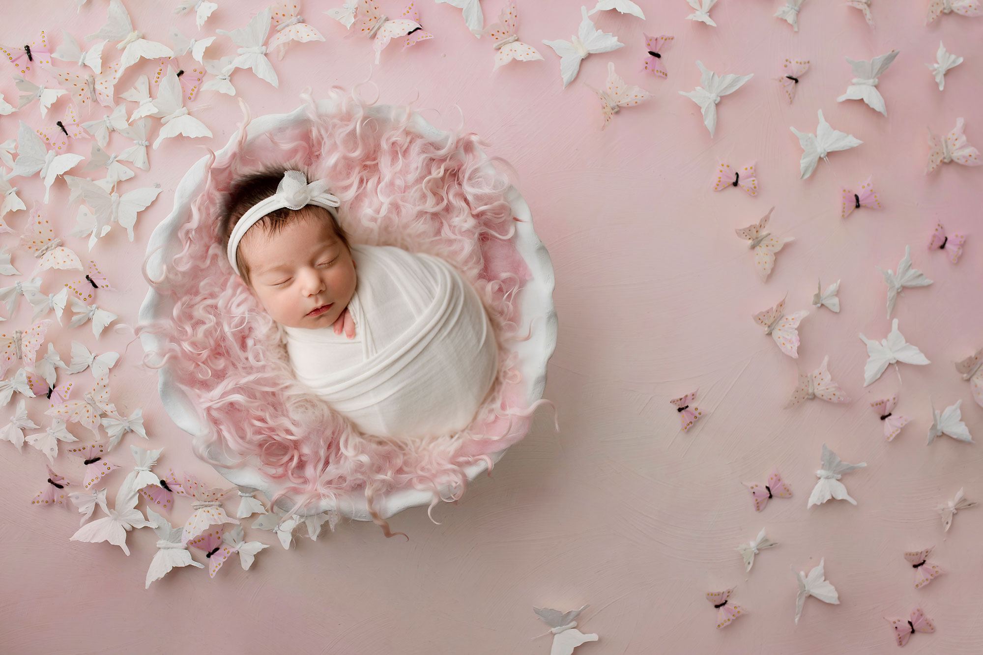NJ newborn photographer capturing baby girl sleeping on a pink blanket surrounded by butterflies